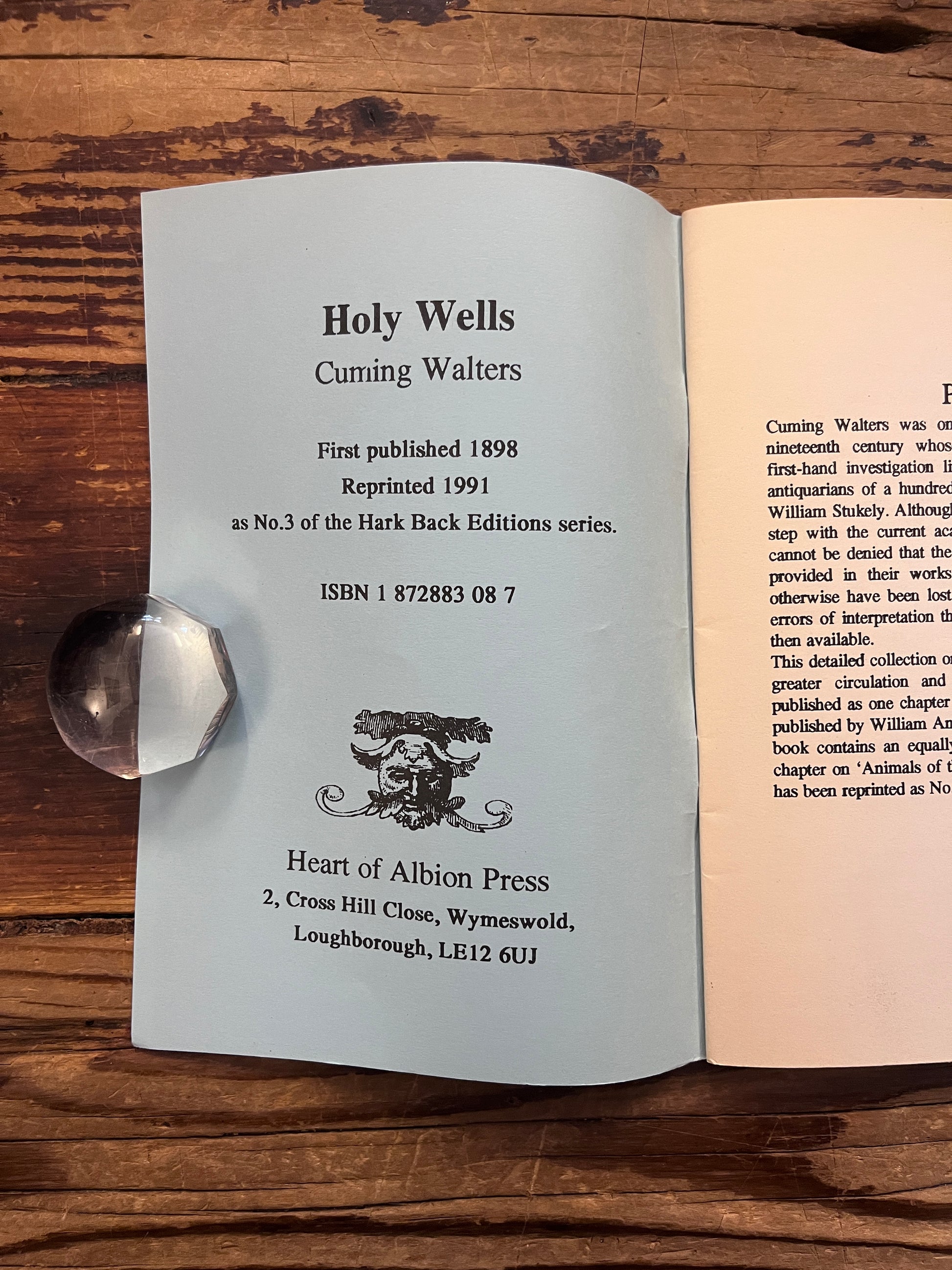 Publishers page of booklet titled 'Holy Wells' by Cuming Walters on a wooden surface