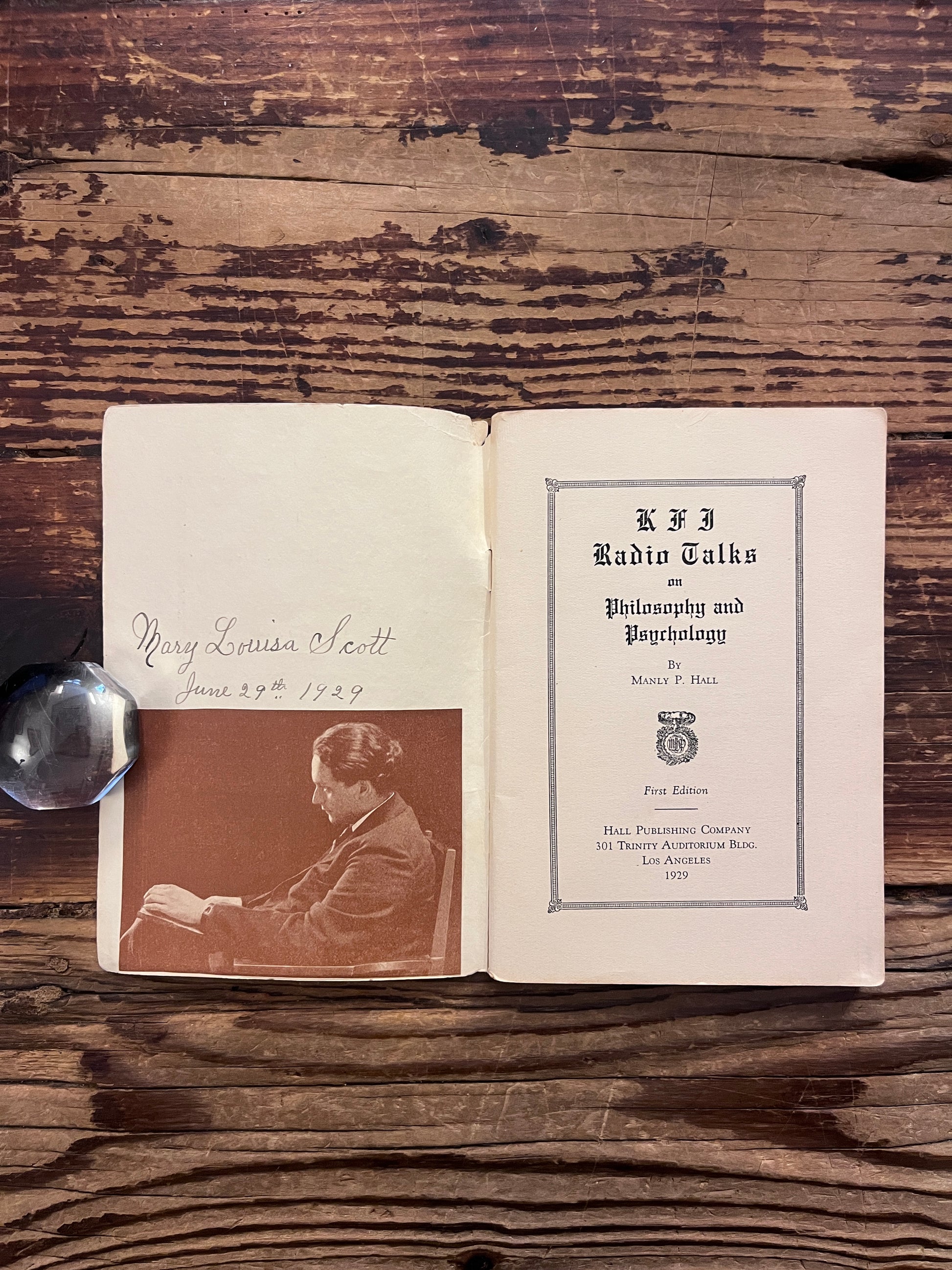 Open booklet titled 'KFI radio talks on philosophy and psychology' by Manly P. Hall on a wooden surface