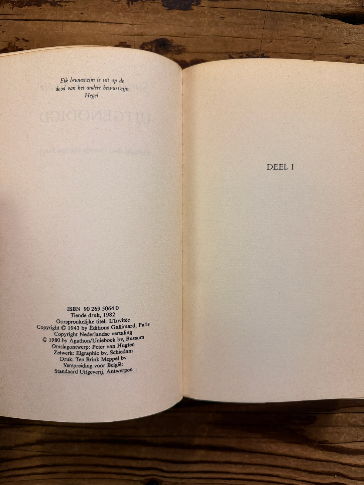 Open boek met de titel 'Uitgenodigd, l'invitée' door Simone de Beauvoir op een houten achtergrond