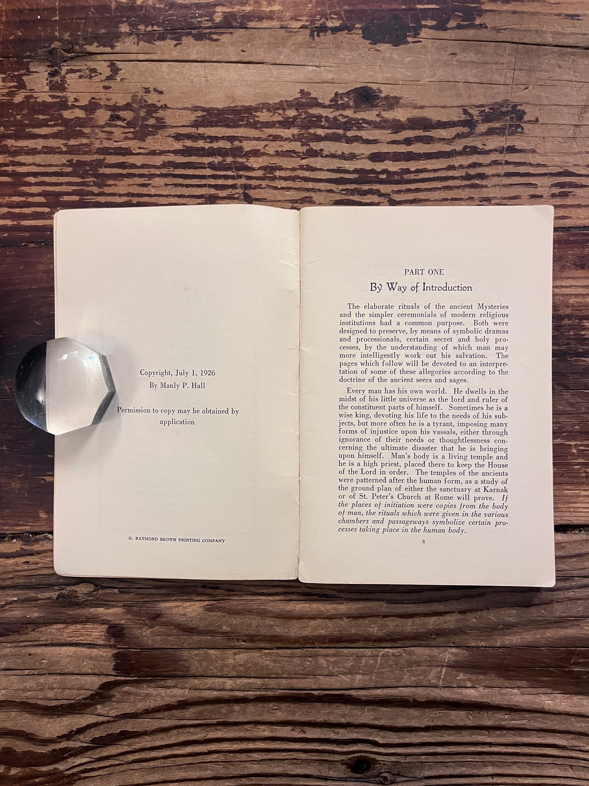 Open booklet titled 'Melchizedek and the mystery of fire' by Manly P. Hall on a wooden surface 