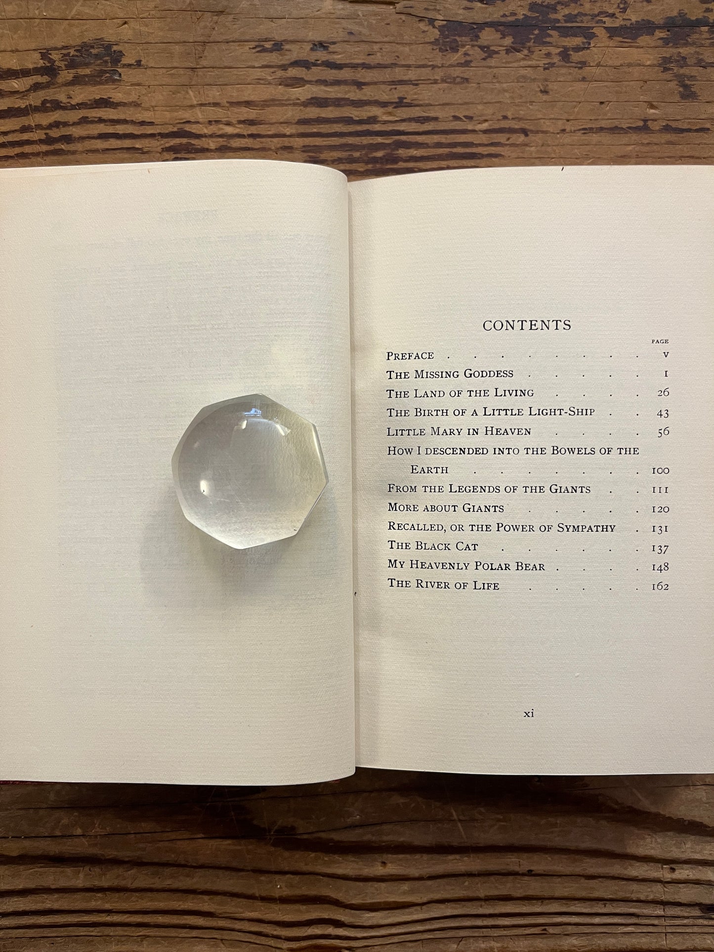 Open book titled 'the missing Goddess and other legends' by Minnie Theobald on a wooden surface