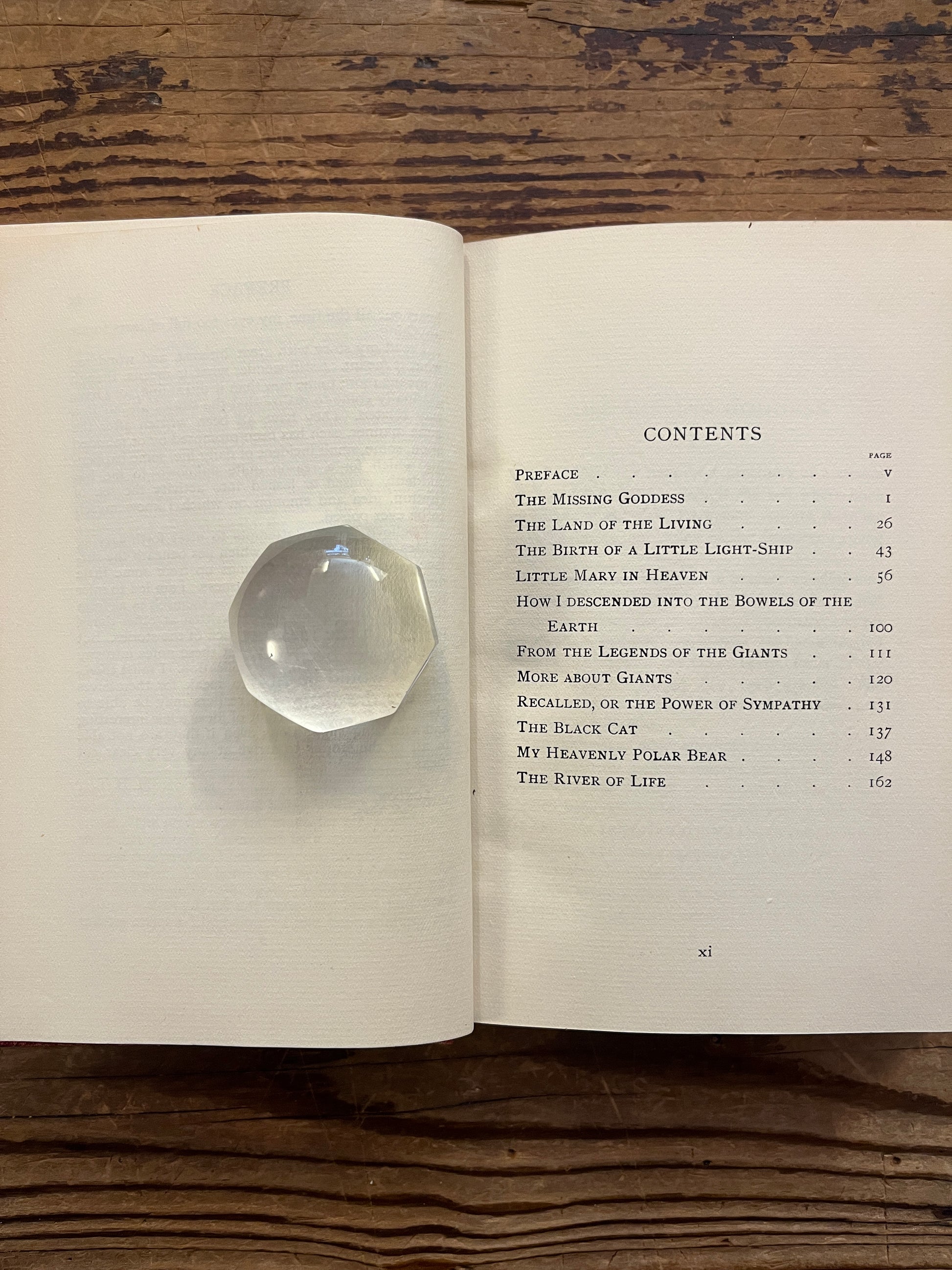 Open book titled 'the missing Goddess and other legends' by Minnie Theobald on a wooden surface