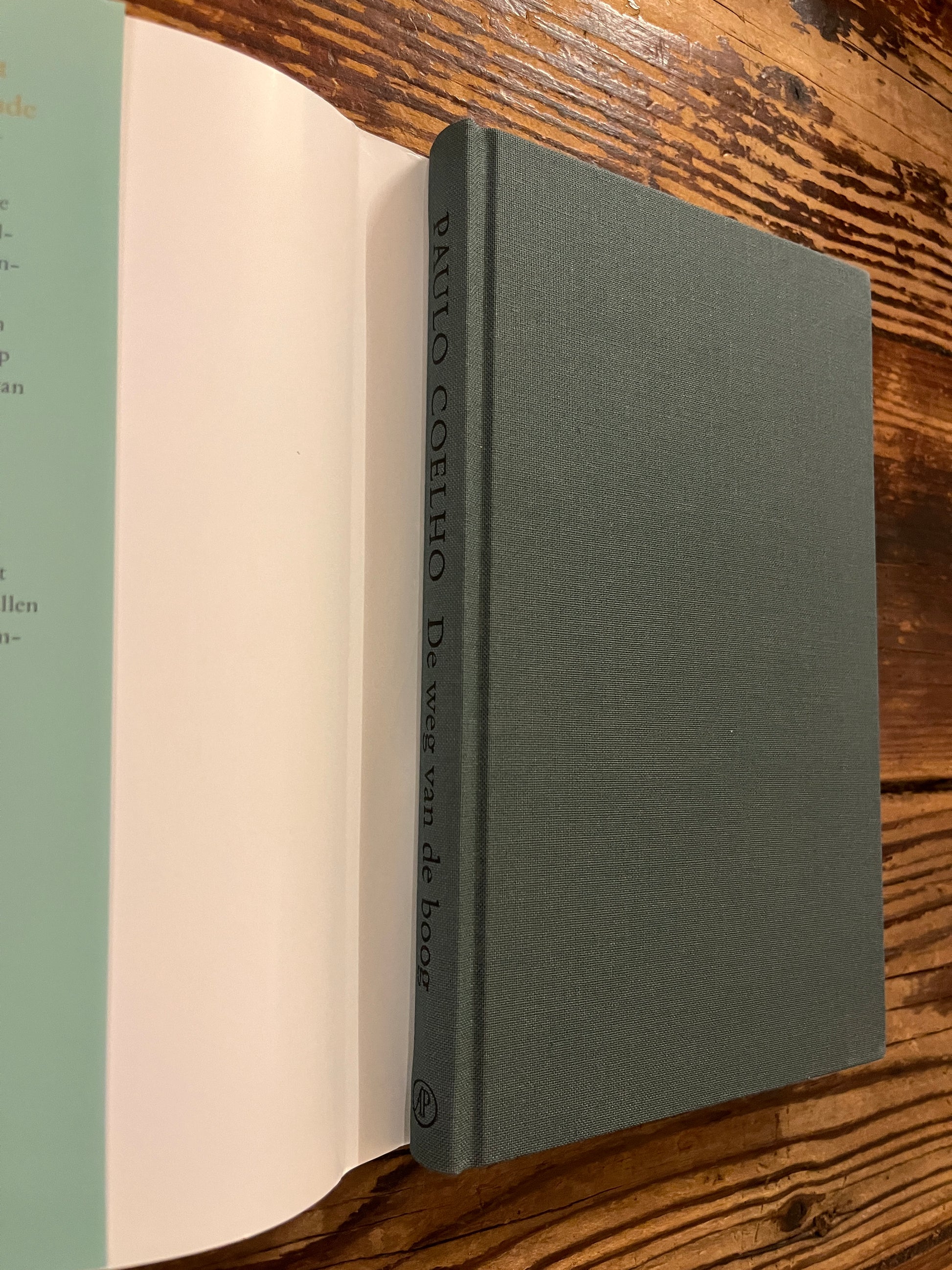 Boek 'de weg van de boog' door Paulo Coelho  zonder stof omslag op een houten achtergrond 