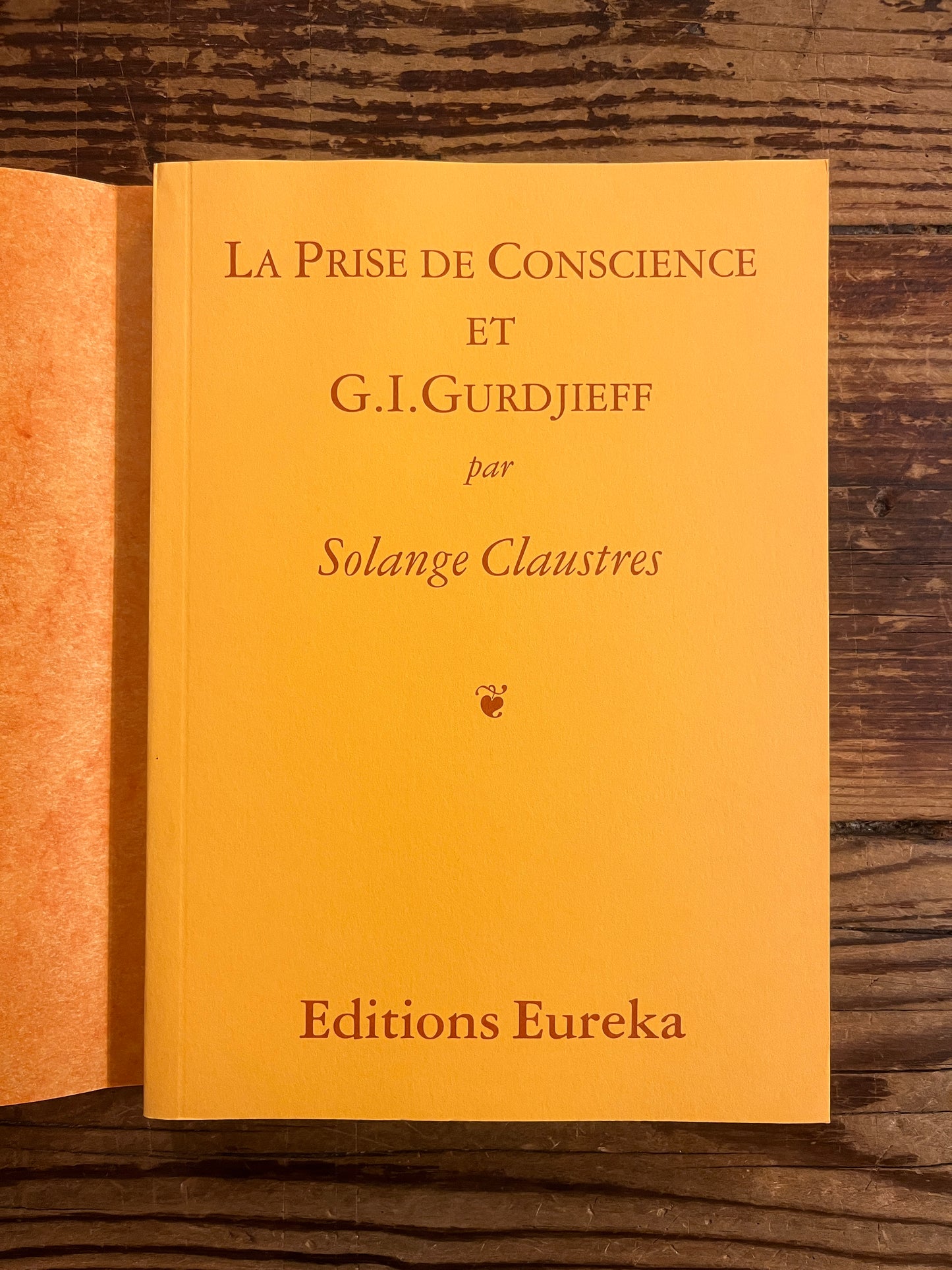 Couverture sans jaquette du livre 'La prise de Conscience et Gurdjieff' par Solange Claustres sur une surface en bois 