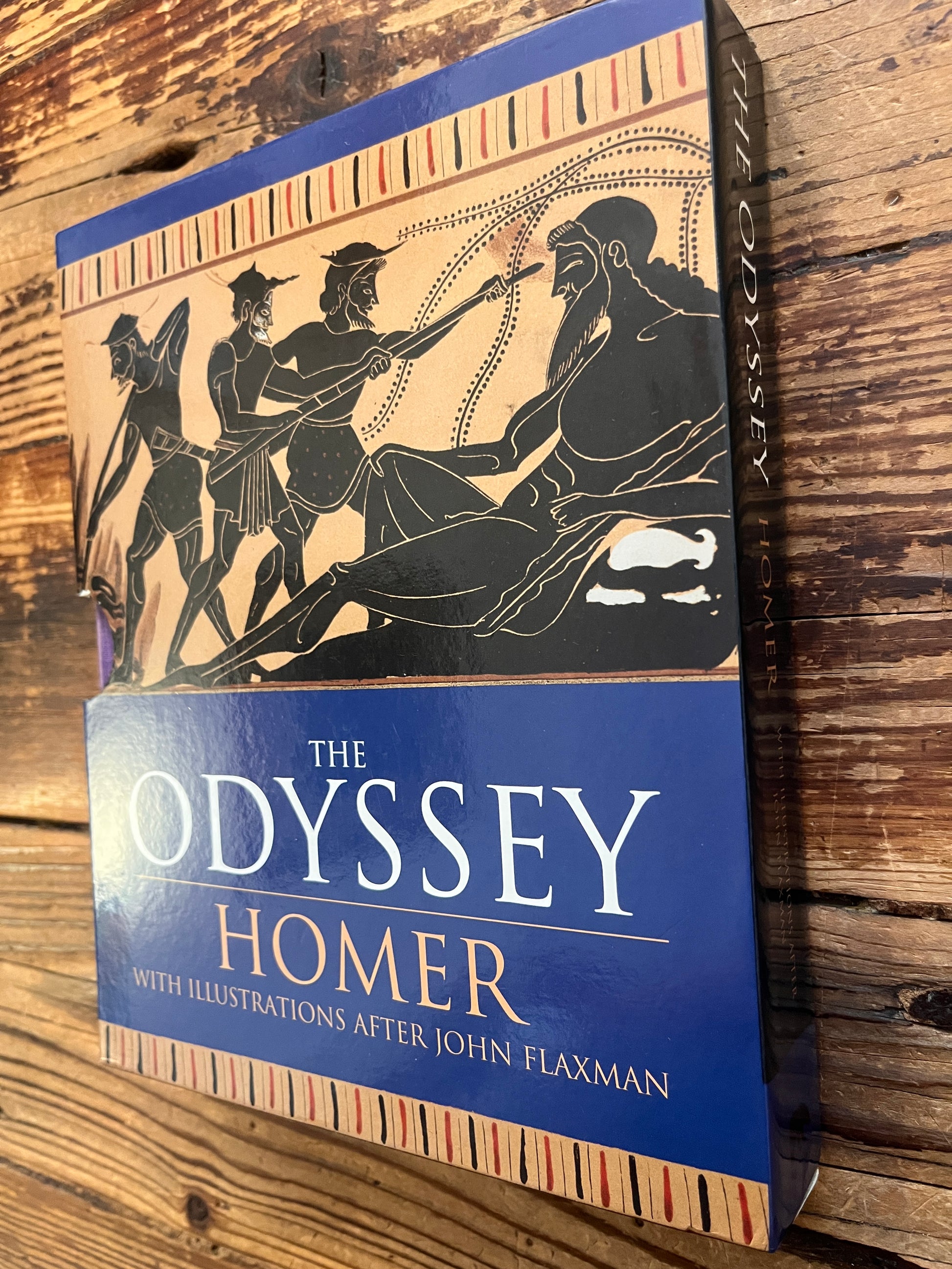Spine and front cover of book titled 'The Odyssey' by Homer and translated by A. Pope on a wooden surface