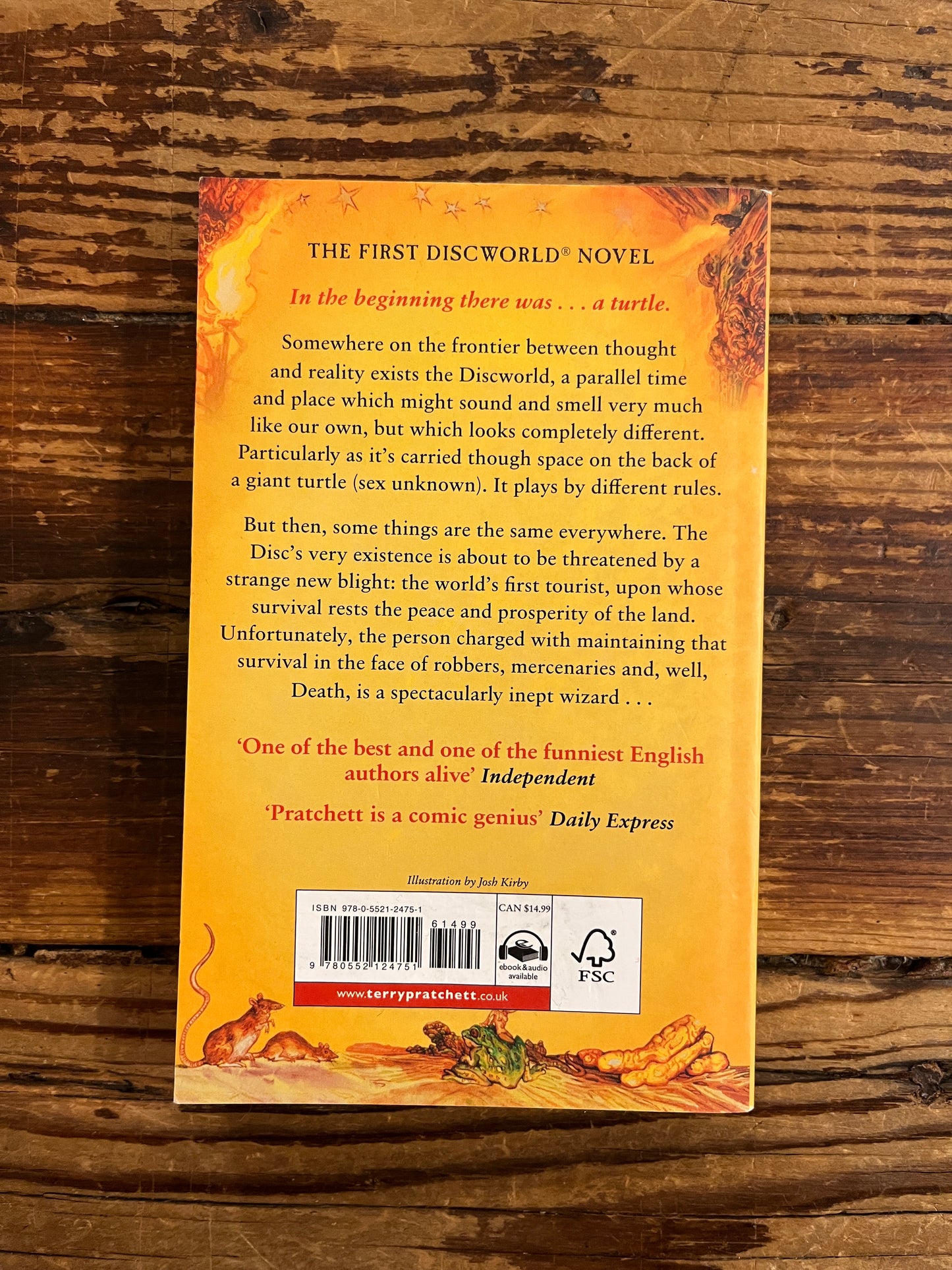 Back cover of book titled 'The Colour of Magic' by Terry Pratchett on a wooden surface