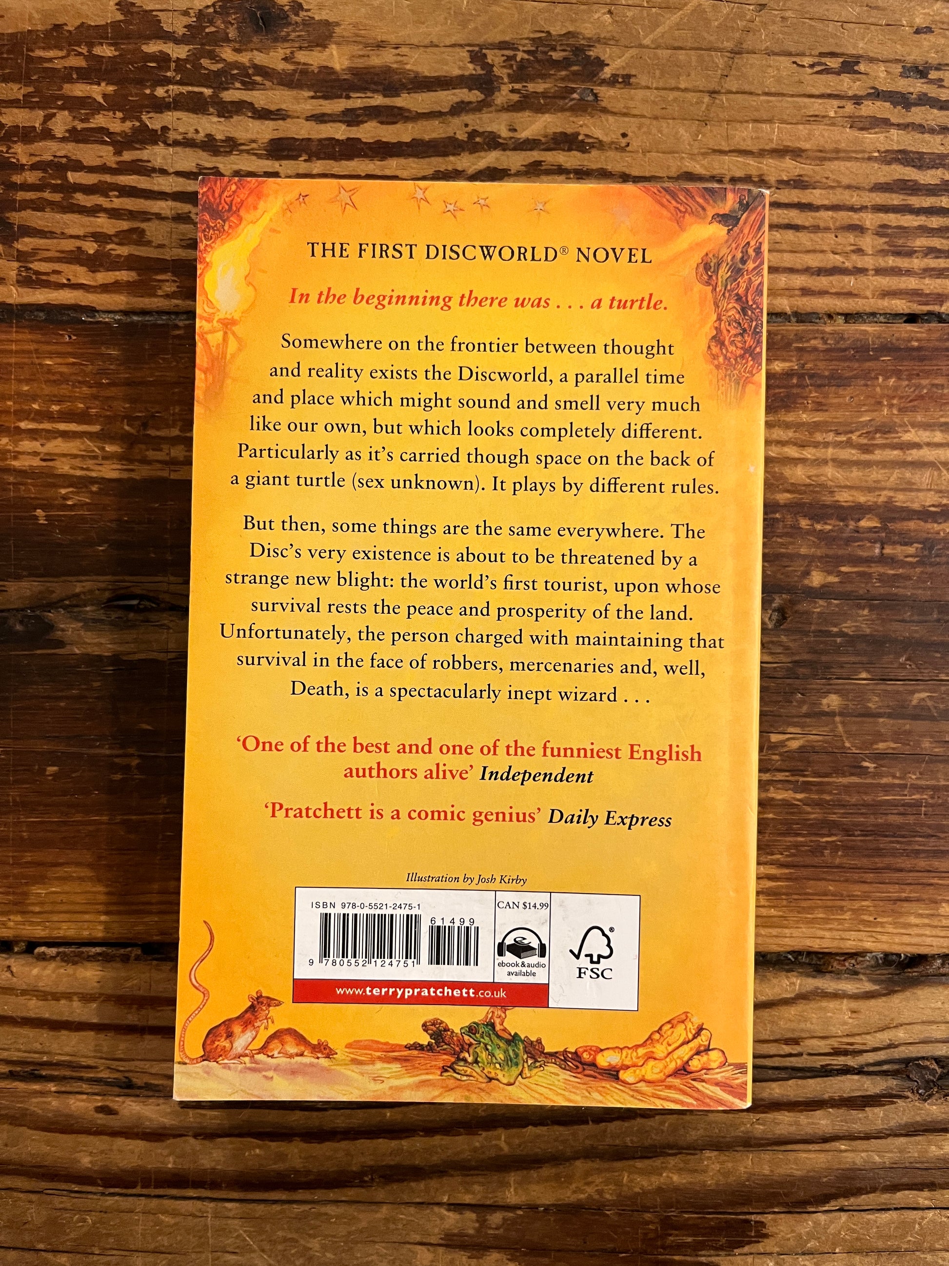 Back cover of book titled 'The Colour of Magic' by Terry Pratchett on a wooden surface