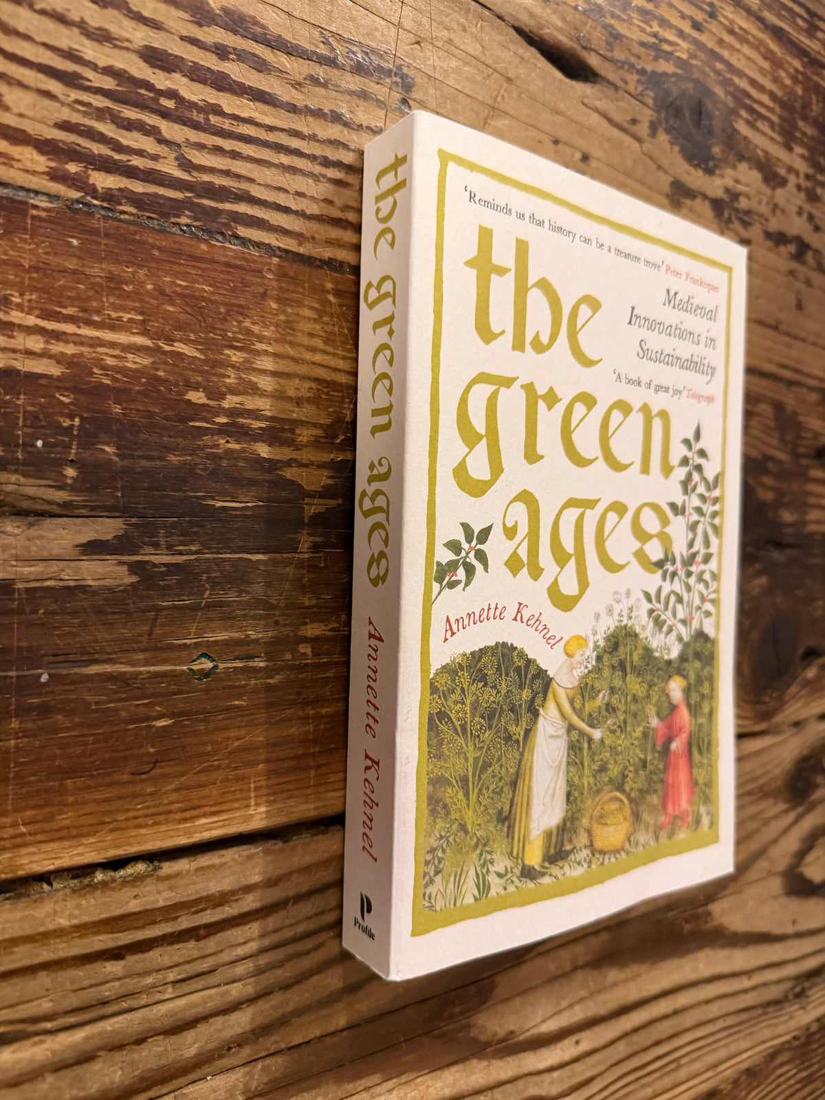 Front cover and spine of the book 'The Green Ages' by Annette Kehnel on a wooden surface