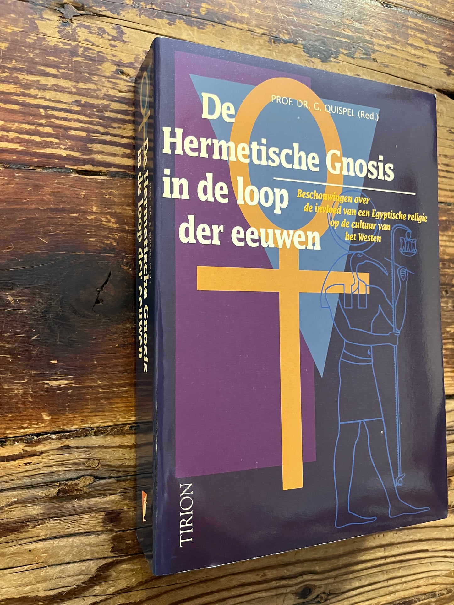 Boek met de titel 'De Hermetische Gnosis in de loop der eeuwen' redactie door Prof. Dr. C. Quispel op een houten achtergrond 