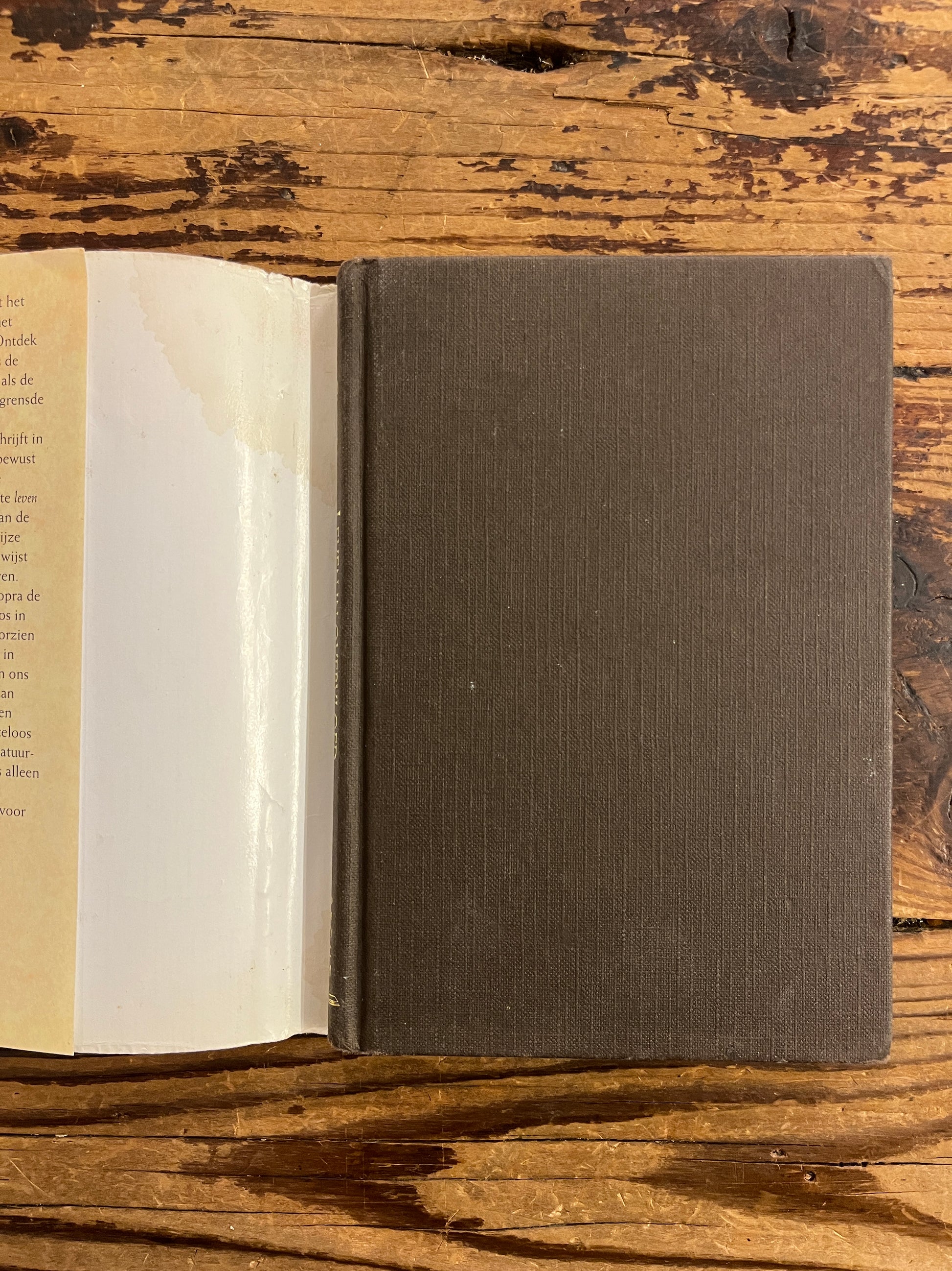 voorkant van boek zonder stof omslag van Boek met de titel 'leven in overvloed' door Deepak Chopra op een houten achtergrond