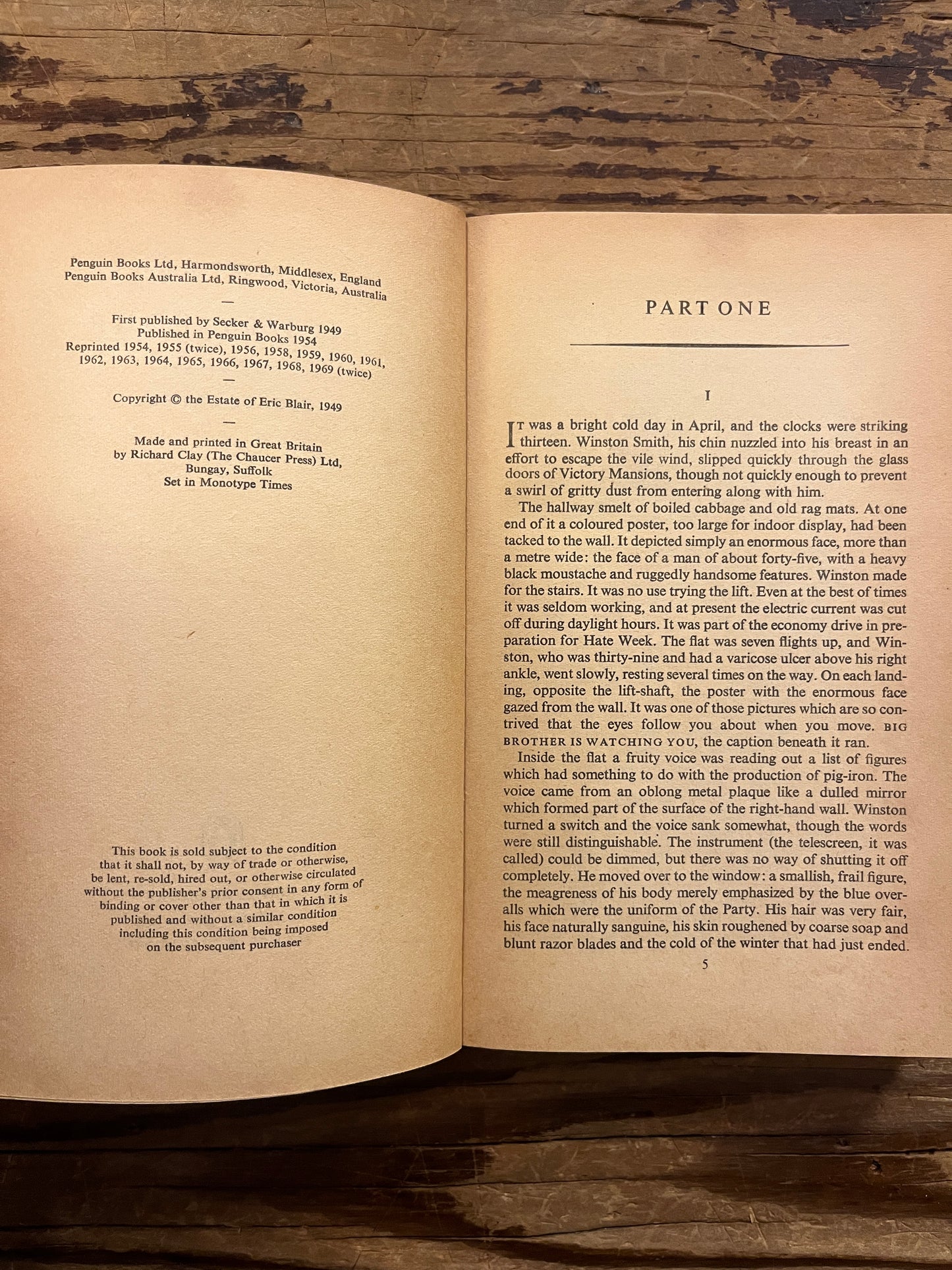 Open book titled 'Nineteen Eighty-Four' by George Orwell on a wooden surface