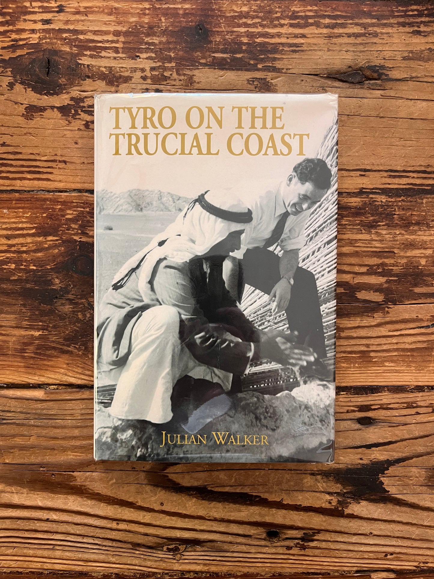 Front cover of book with the title 'Tyro on the Trucial Coast' by Julian Walker on a wooden surface