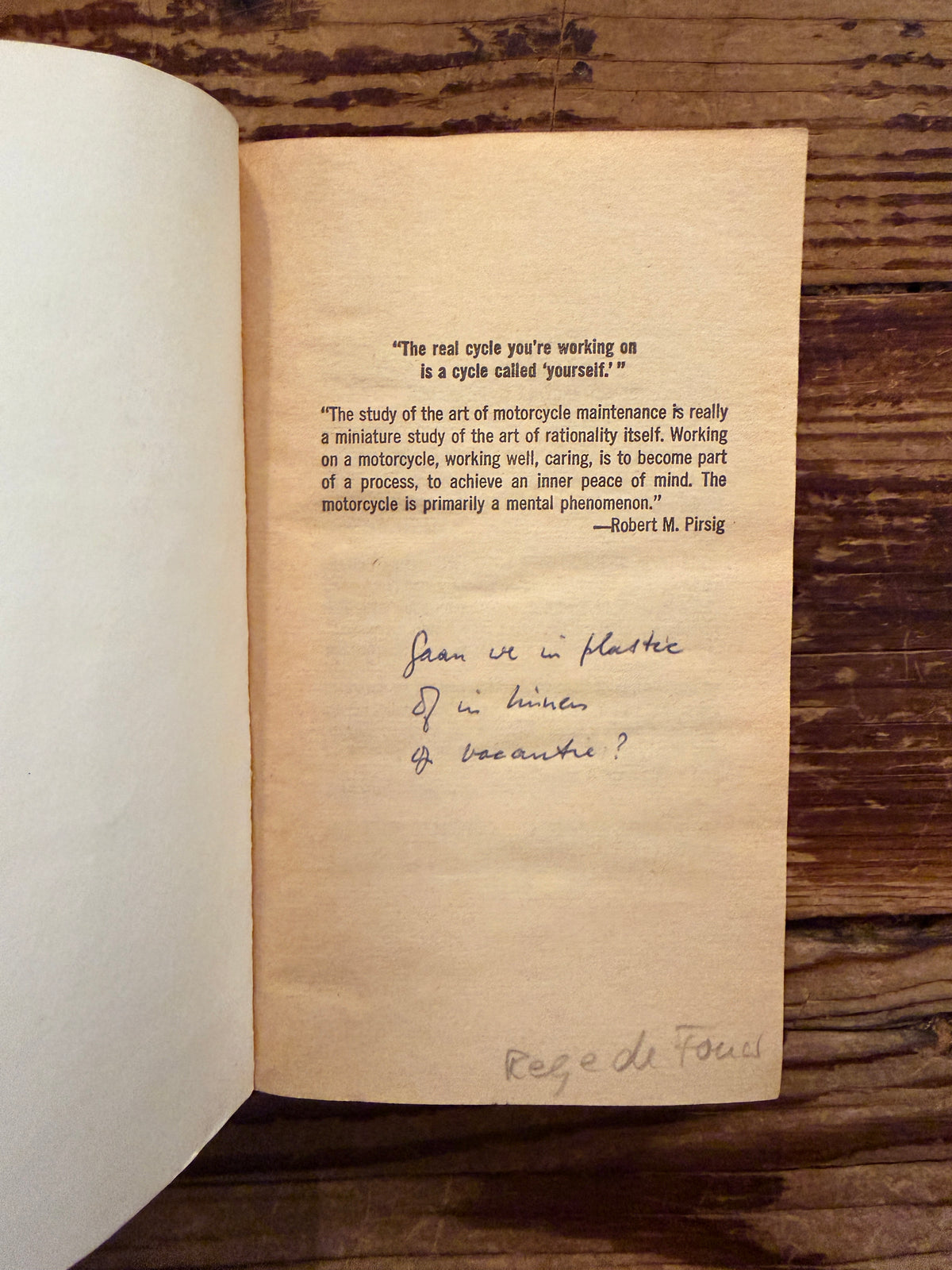 first page of a book titled 'Zen and the Art of Motorcycle Maintenance' by Robert M. Pirsig on a wooden surface