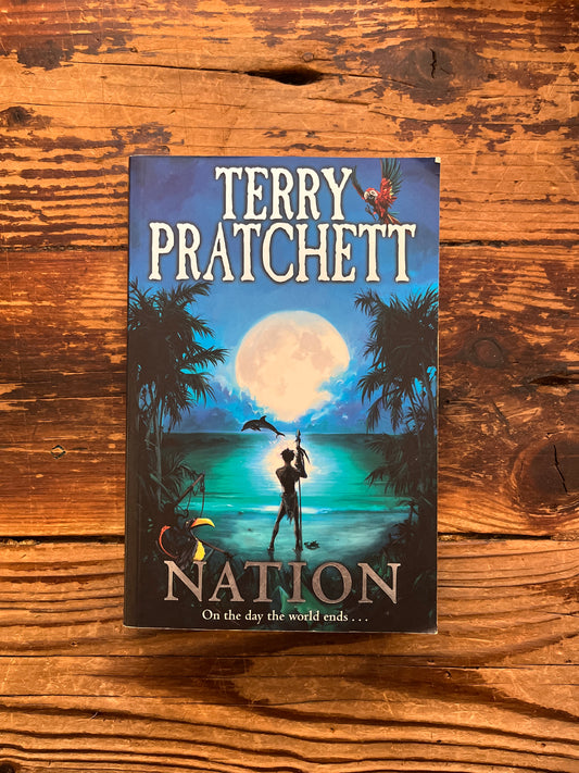 Front cover of book titled 'Nation' by Terry Pratchett on a wooden surface