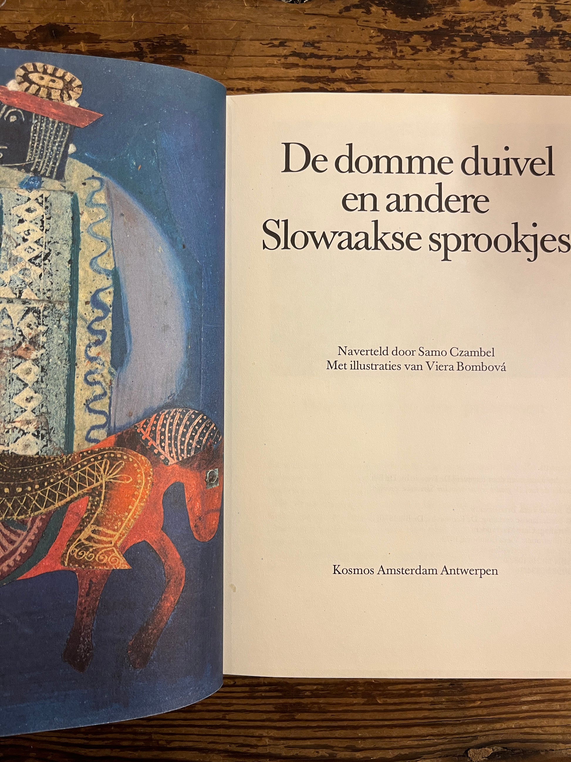 Open boek boek met de titel 'De domme duivel en andere Slowaakse sprookjes' op een houten tafel