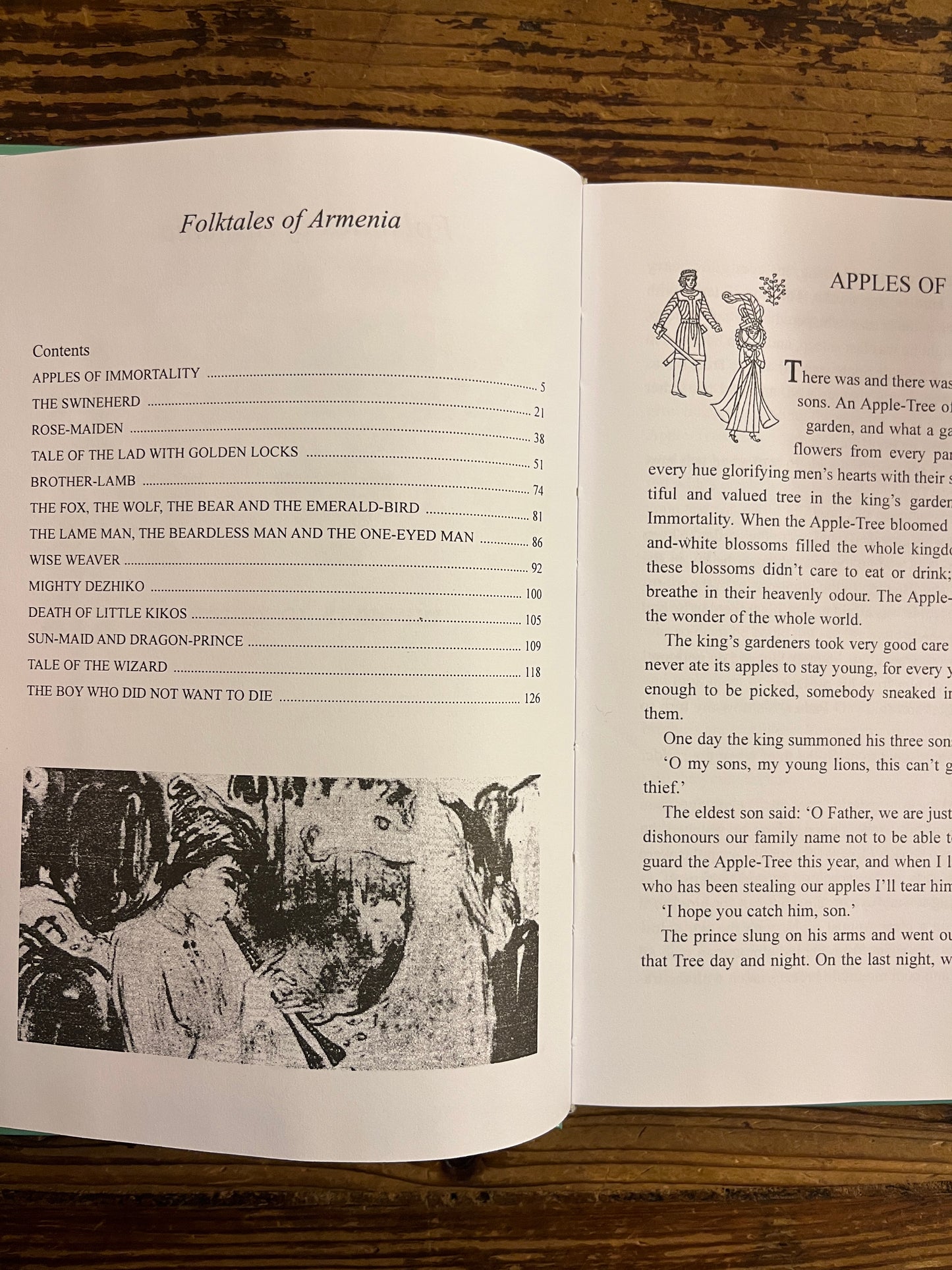 Open book titled 'Folktales of Armenia' on a wooden surface