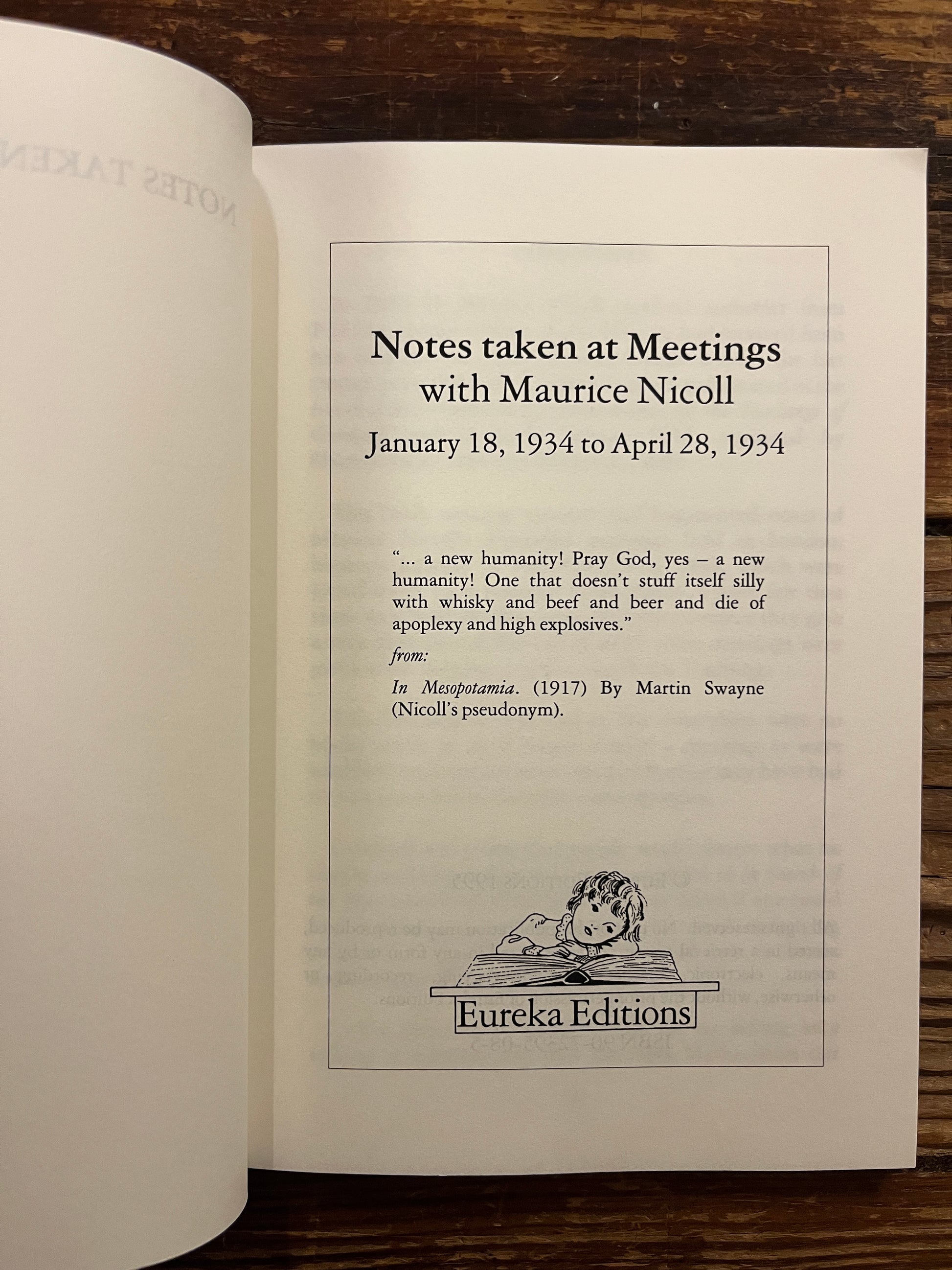 Open book titled'Notes taken at meetings' by Maurice Nicoll on wooden surface 
