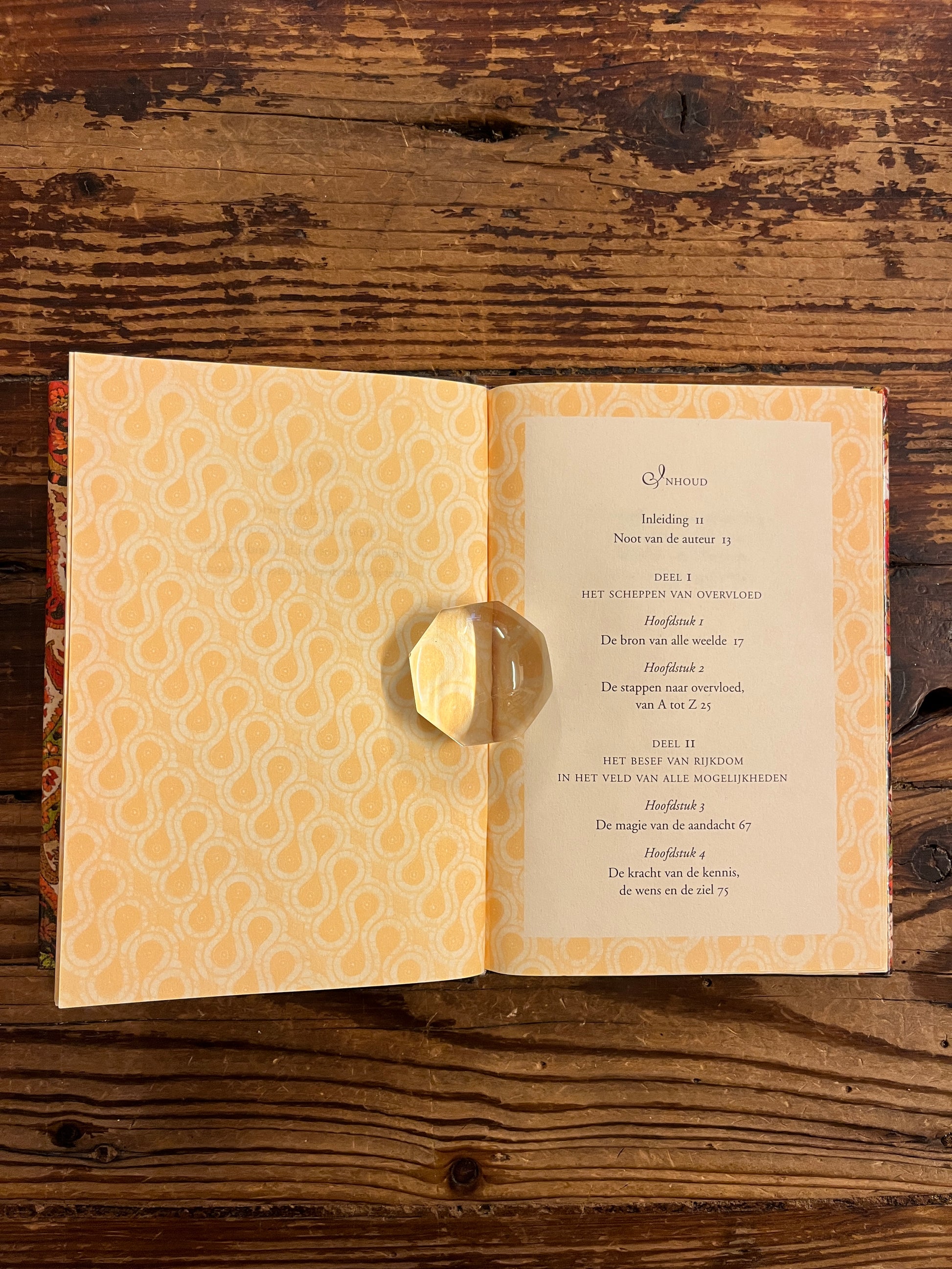 Open Boek met de titel 'leven in overvloed' door Deepak Chopra op een houten achtergrond