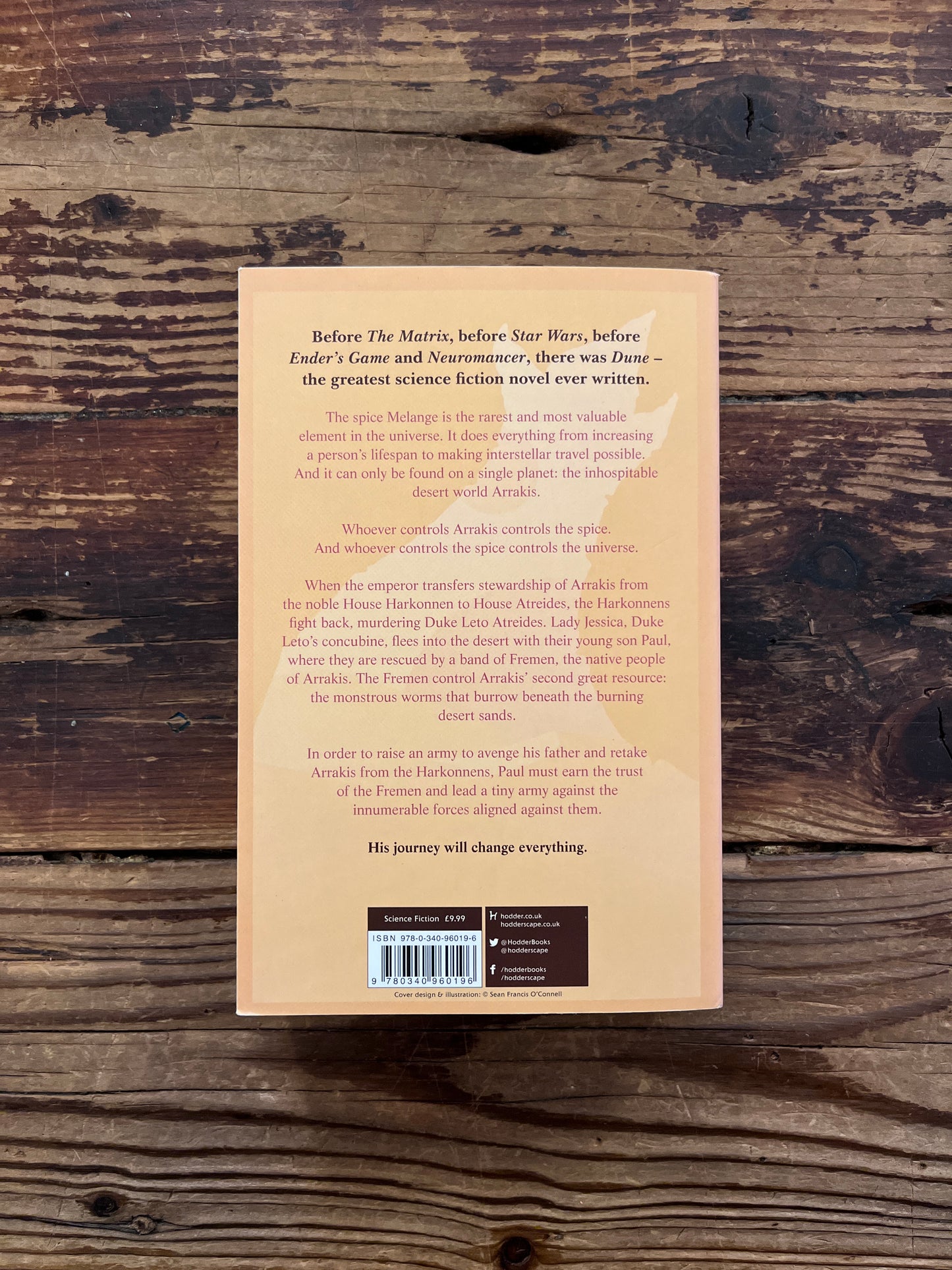 Back cover of book titled 'Dune' by Frank herbert on a wooden surface 