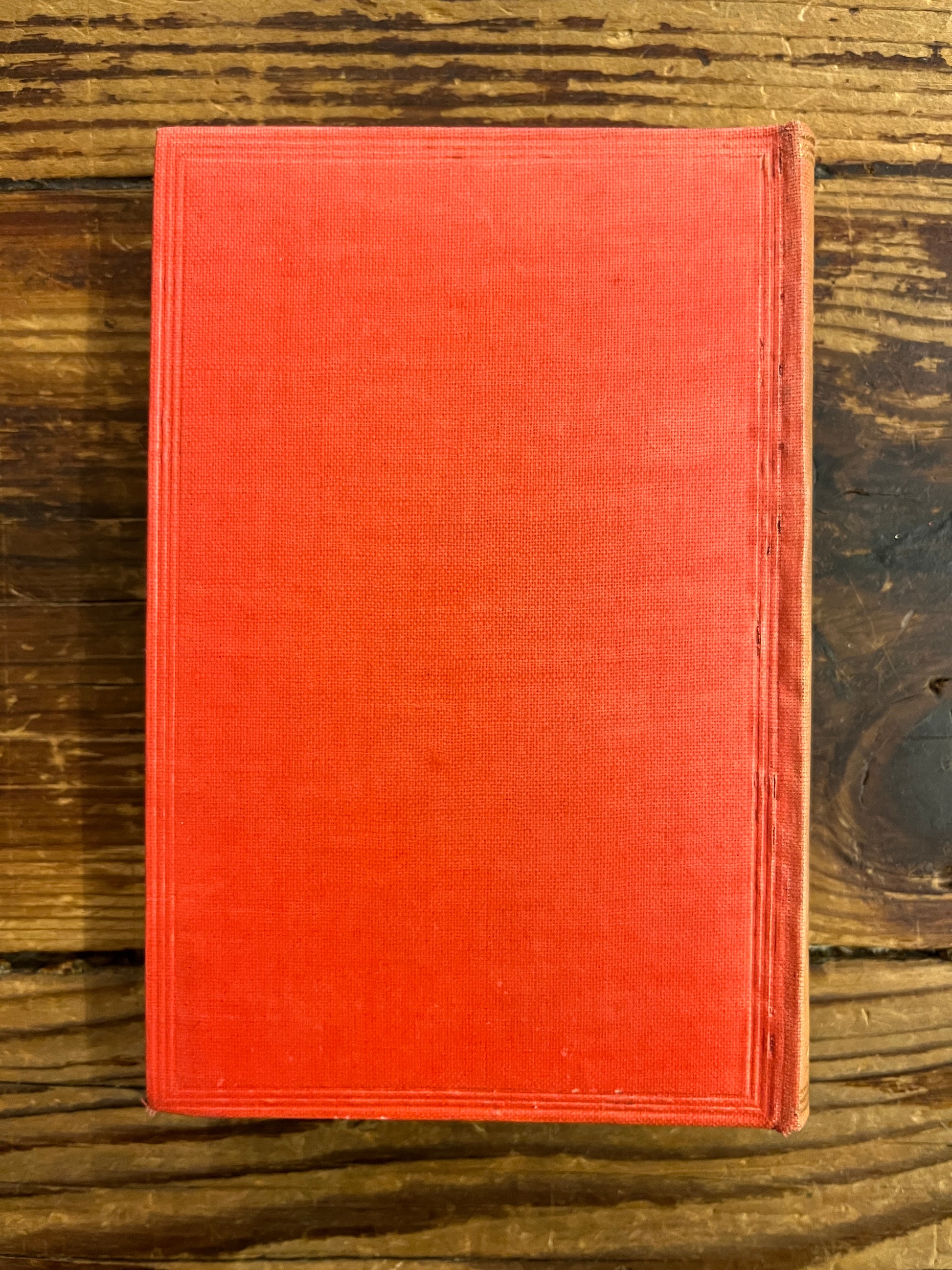 Back cover of a 1922 macmillan & co miniature edition of 'Alice's adventures in wonderland' by Lewis Carroll on a wooden surface