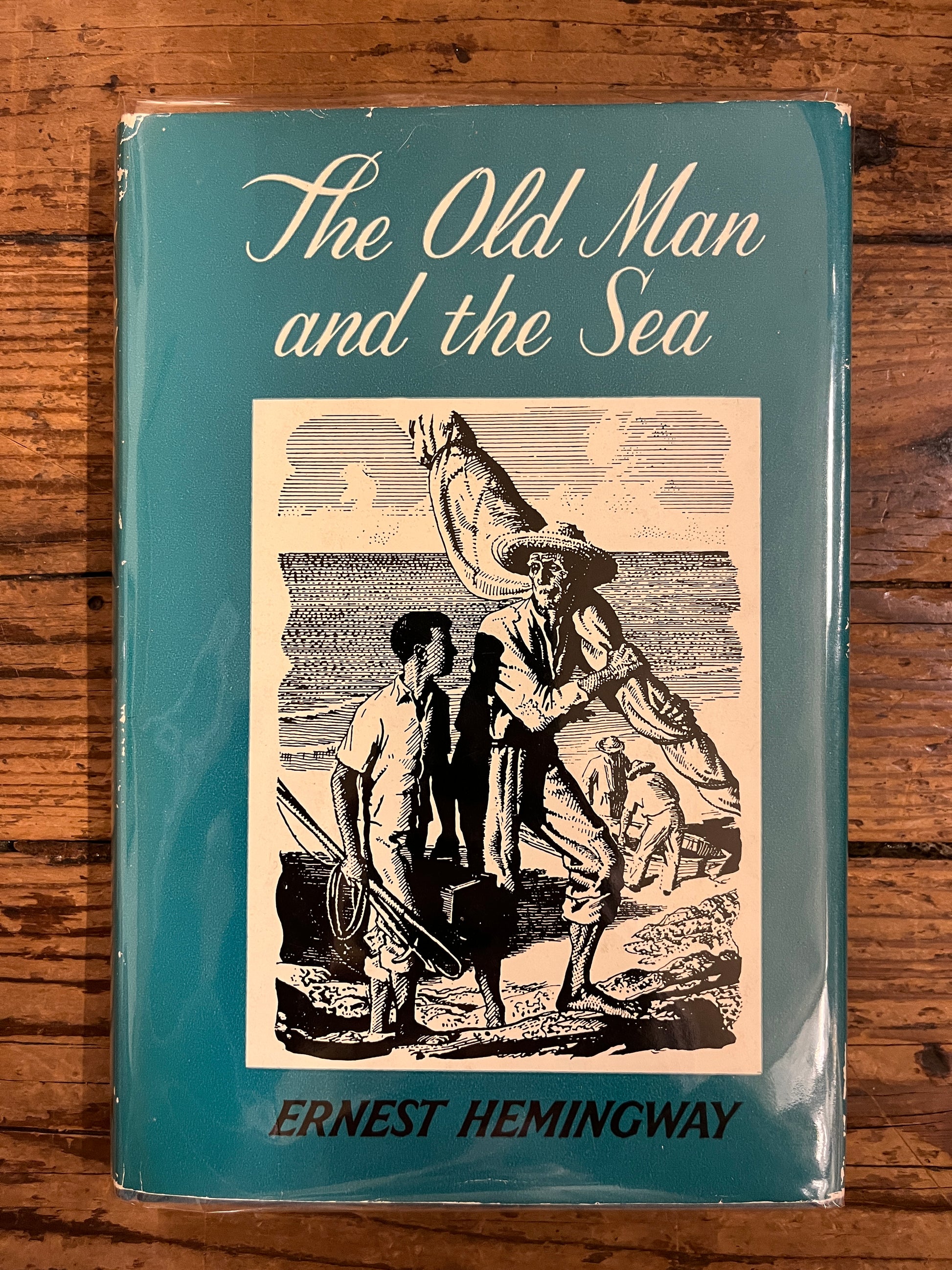 photo of the cover of the book "the old man and the sea" on a wooden background