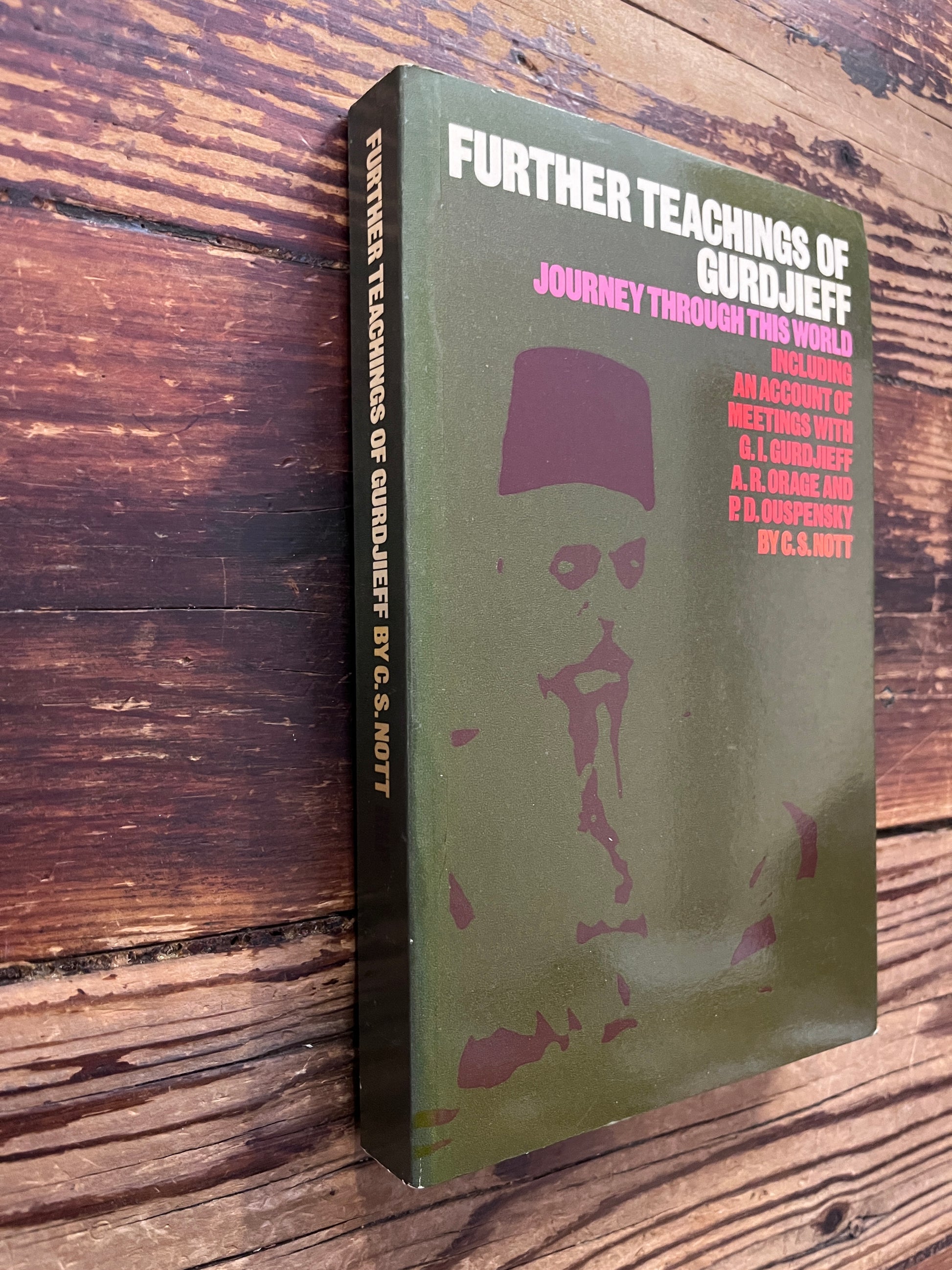 Front cover and spine of book titled 'Further Teachings of Gurdjieff' by C.S. Nott with an olive green cover, placed on a rustic dark wood background.