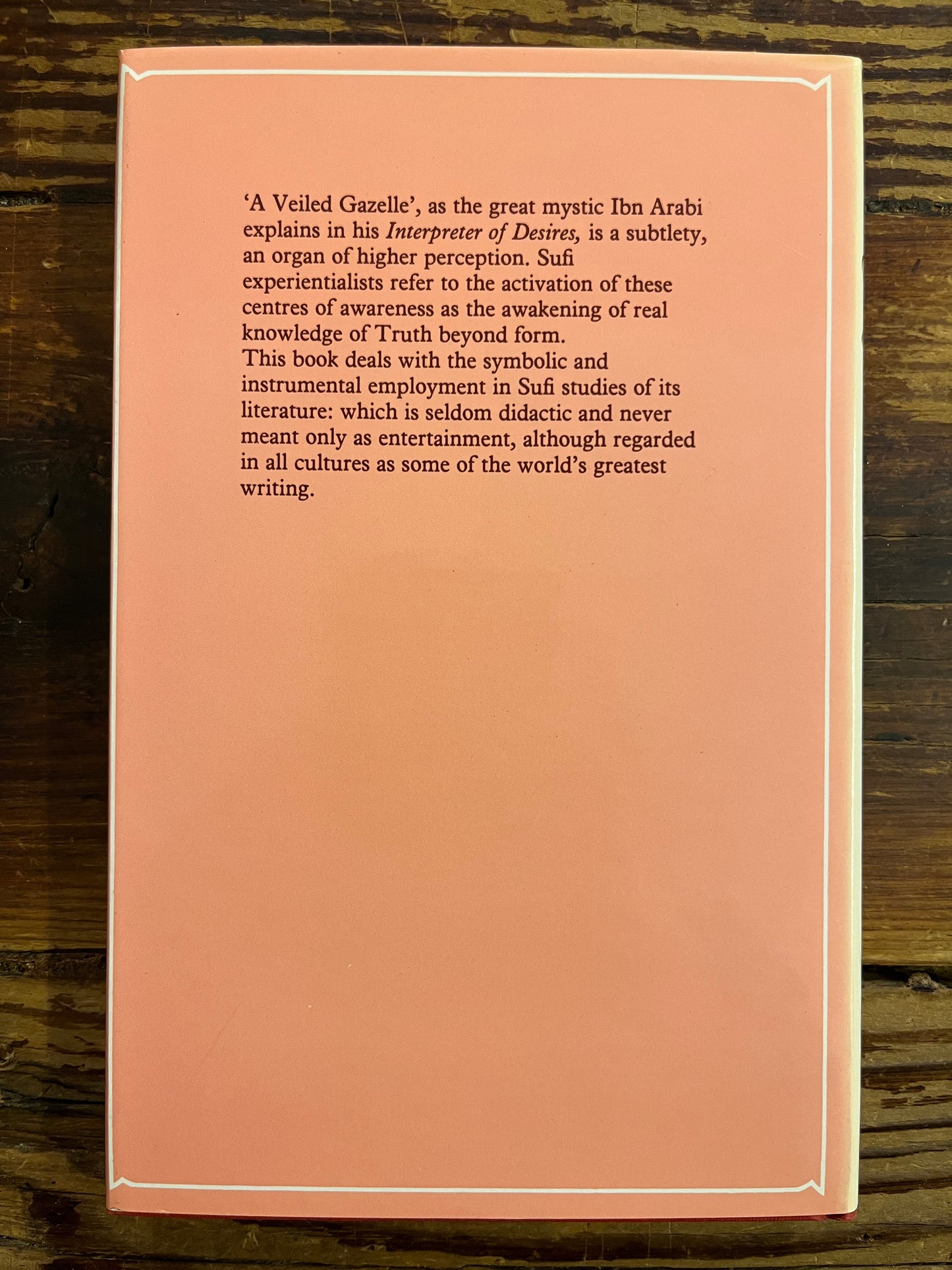 back cover of book titled 'A Veiled Gazette' by Idries Shah with text on a wooden surface