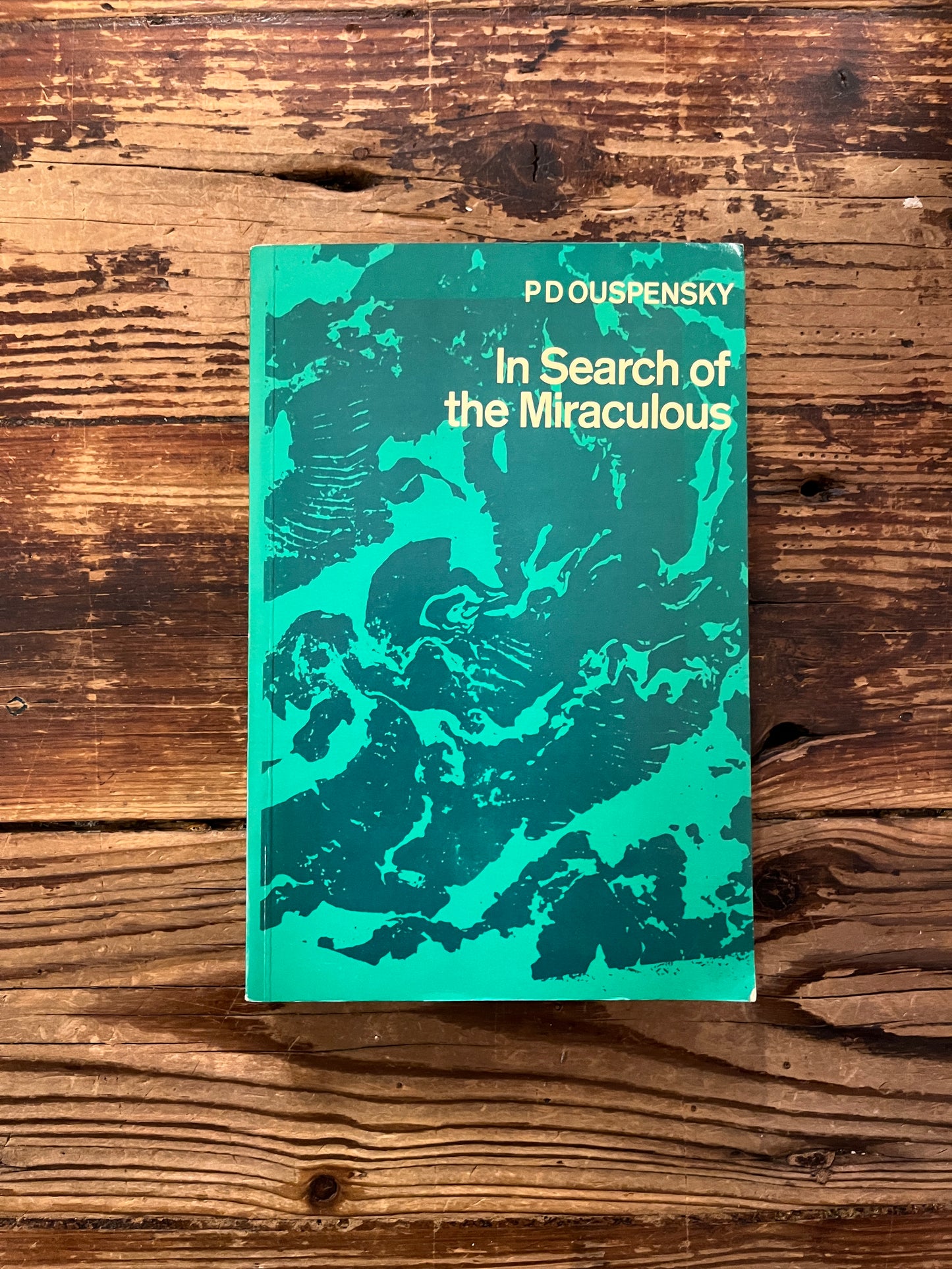 Front cover of book titled 'In Search of the Miraculous' by P.D. Ouspensky on a wooden surface