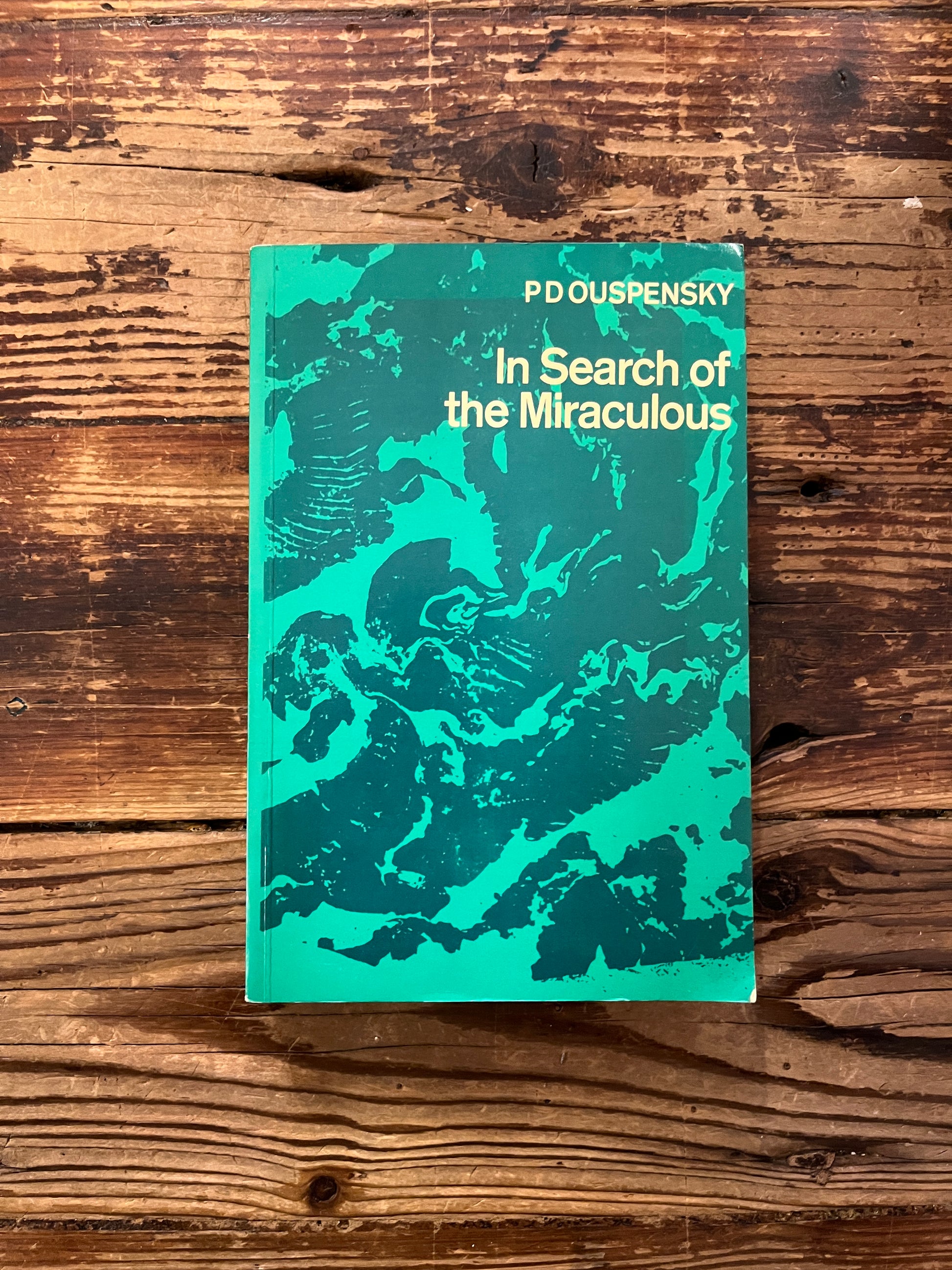 Front cover of book titled 'In Search of the Miraculous' by P.D. Ouspensky on a wooden surface