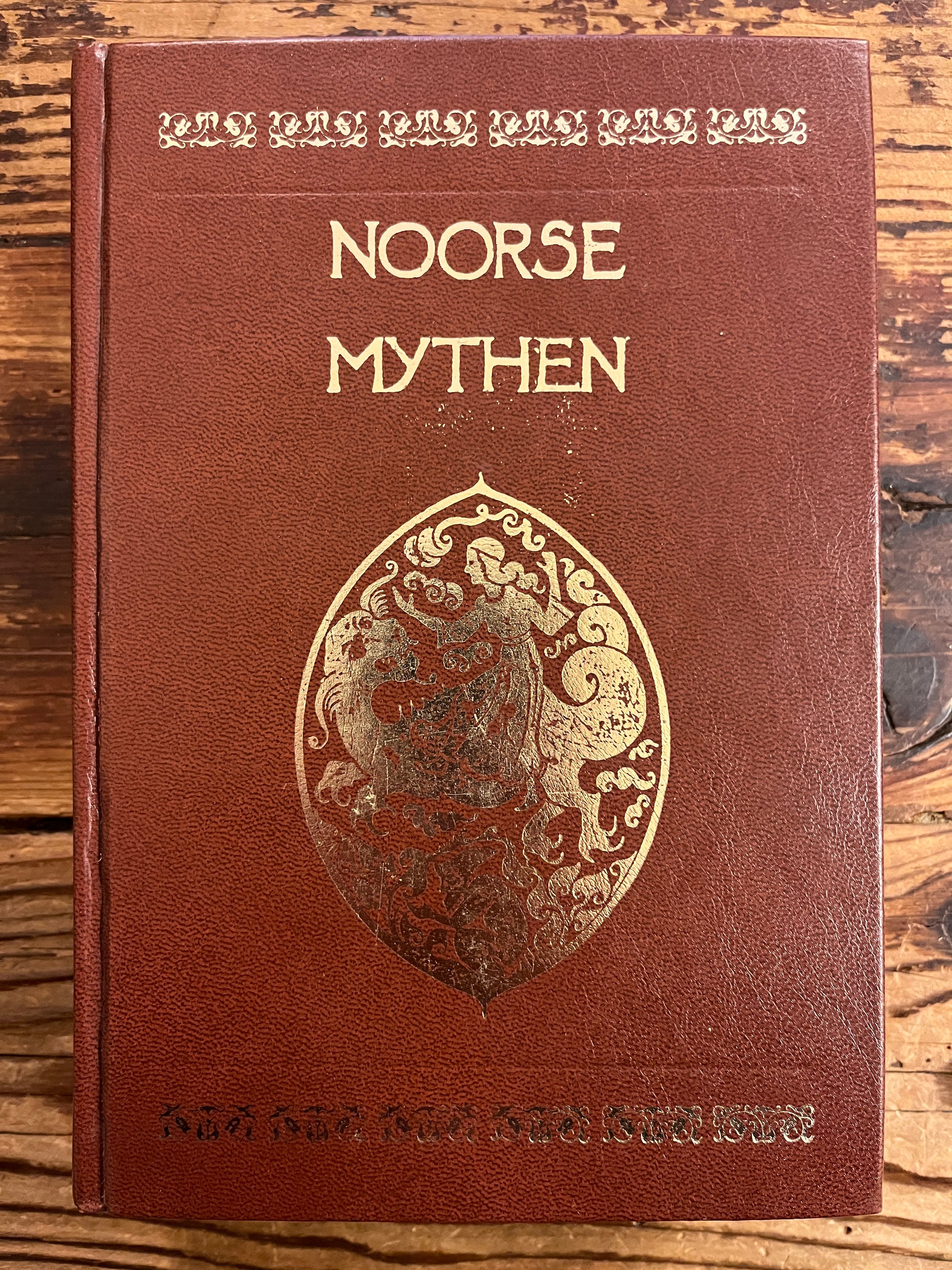Brown book titled 'Noorse Mythen' on a wooden surface