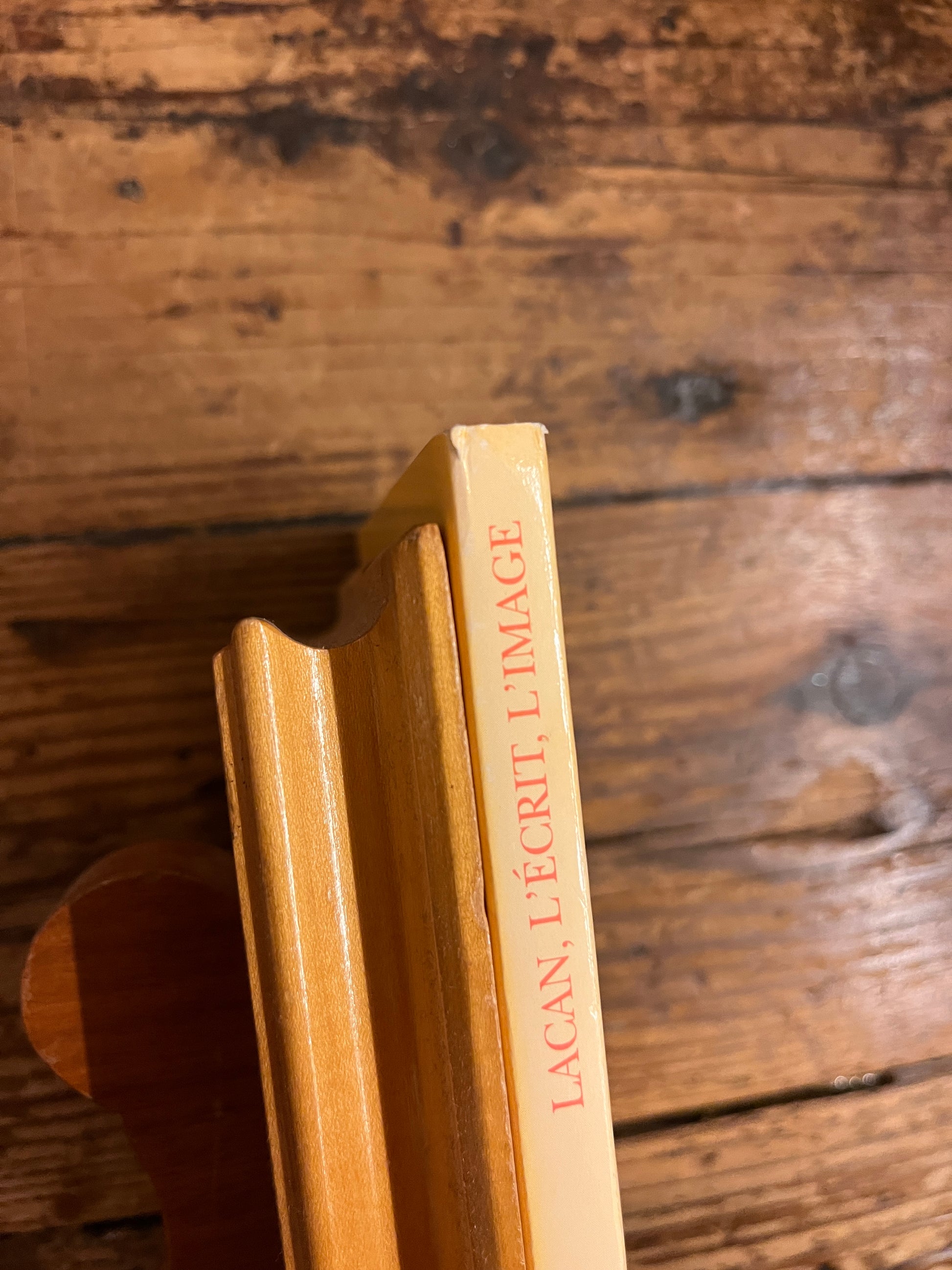 details d'une imperfection du livre  "lacan l'ecrit et l'image" sur fond de bois. le haut du dos du livre est tres legerement dechire sur 1/2 mm 