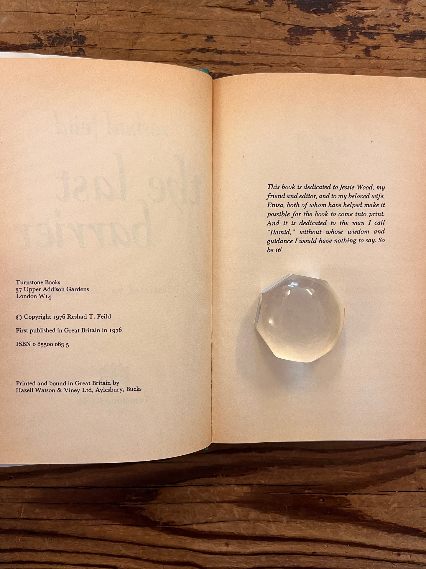 Open book with the title 'the Last Barrier,a sufi journey' by Reshad Feild on a wooden surface 