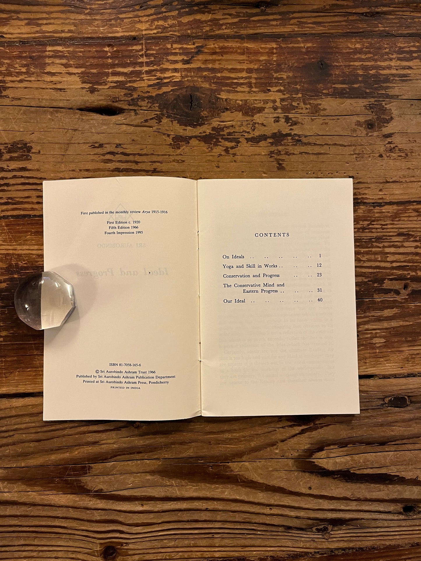 Open book showing the contents of book titled 'Ideal and Progress' by Sri Aurobindo on a wooden surface
