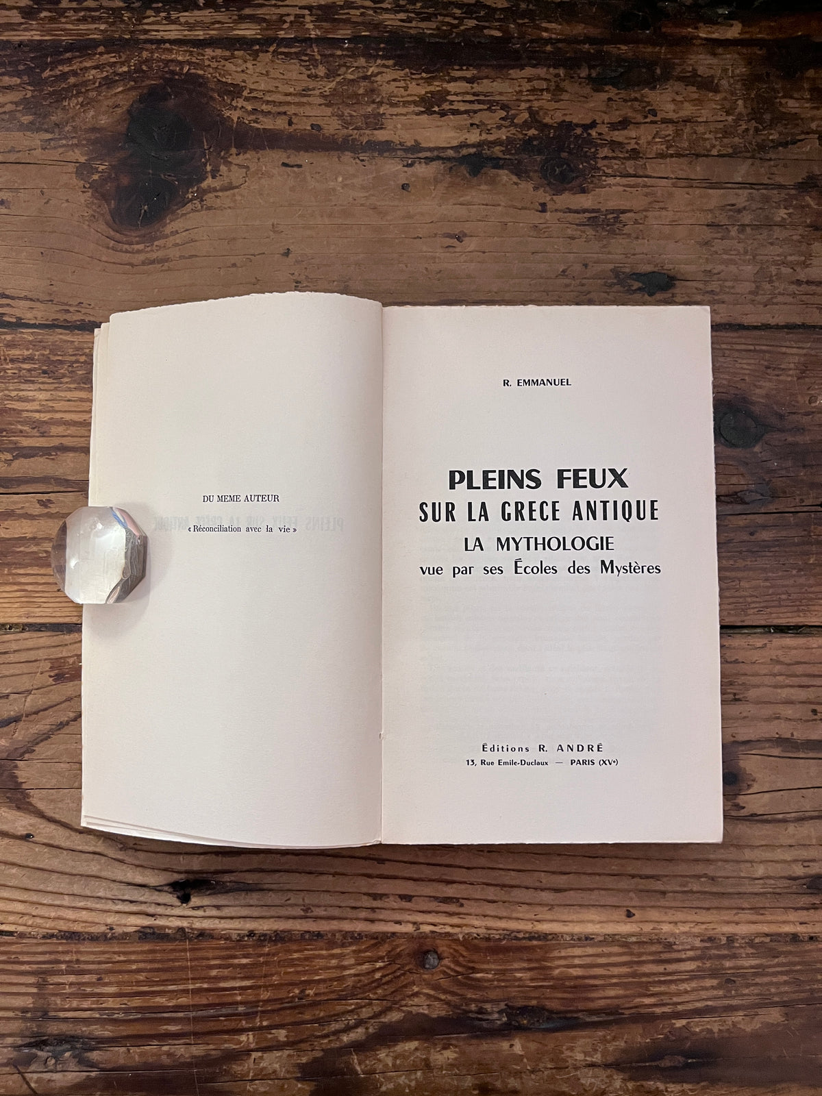 photo de la page de titre du livre "la mythlogie vue par ses ecoles des mysteres "  sur fond de bois