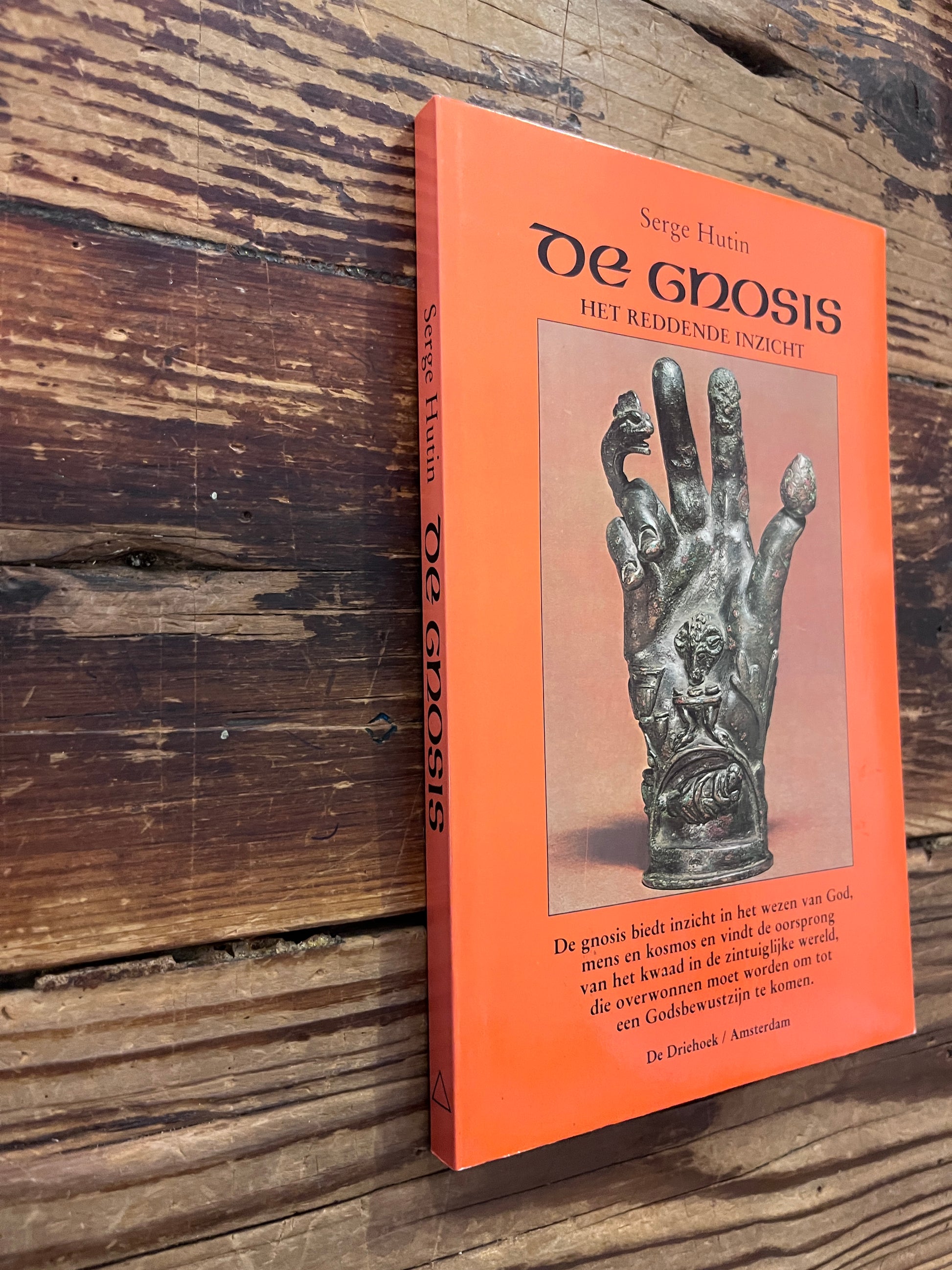 Voorkant en rug van een boek met de titel 'De Gnosis' door Serge Hutin op een houten achtergrond 