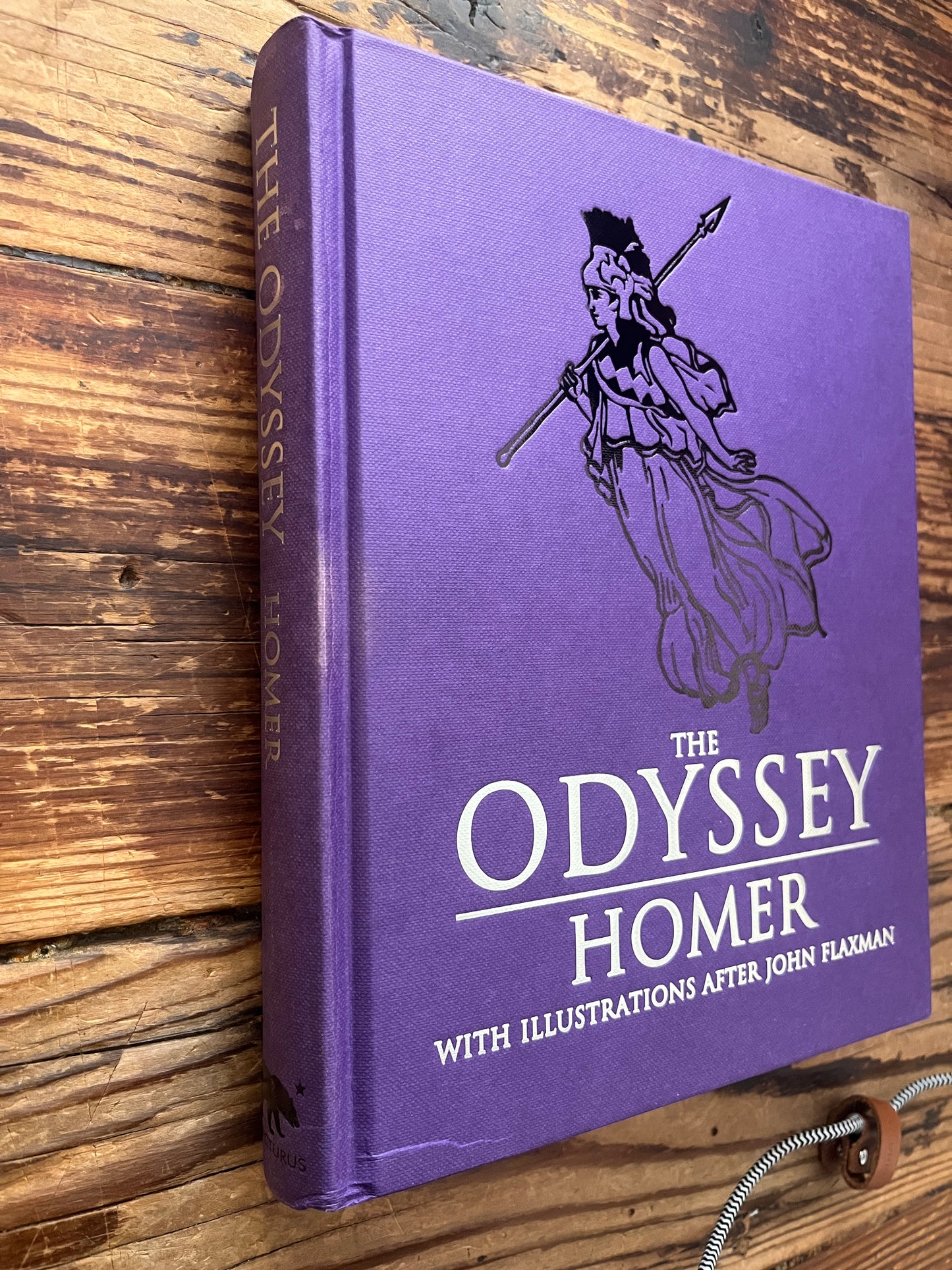 Spine and front cover of book titled 'The Odyssey' by Homer and translated by A. Pope on a wooden surface