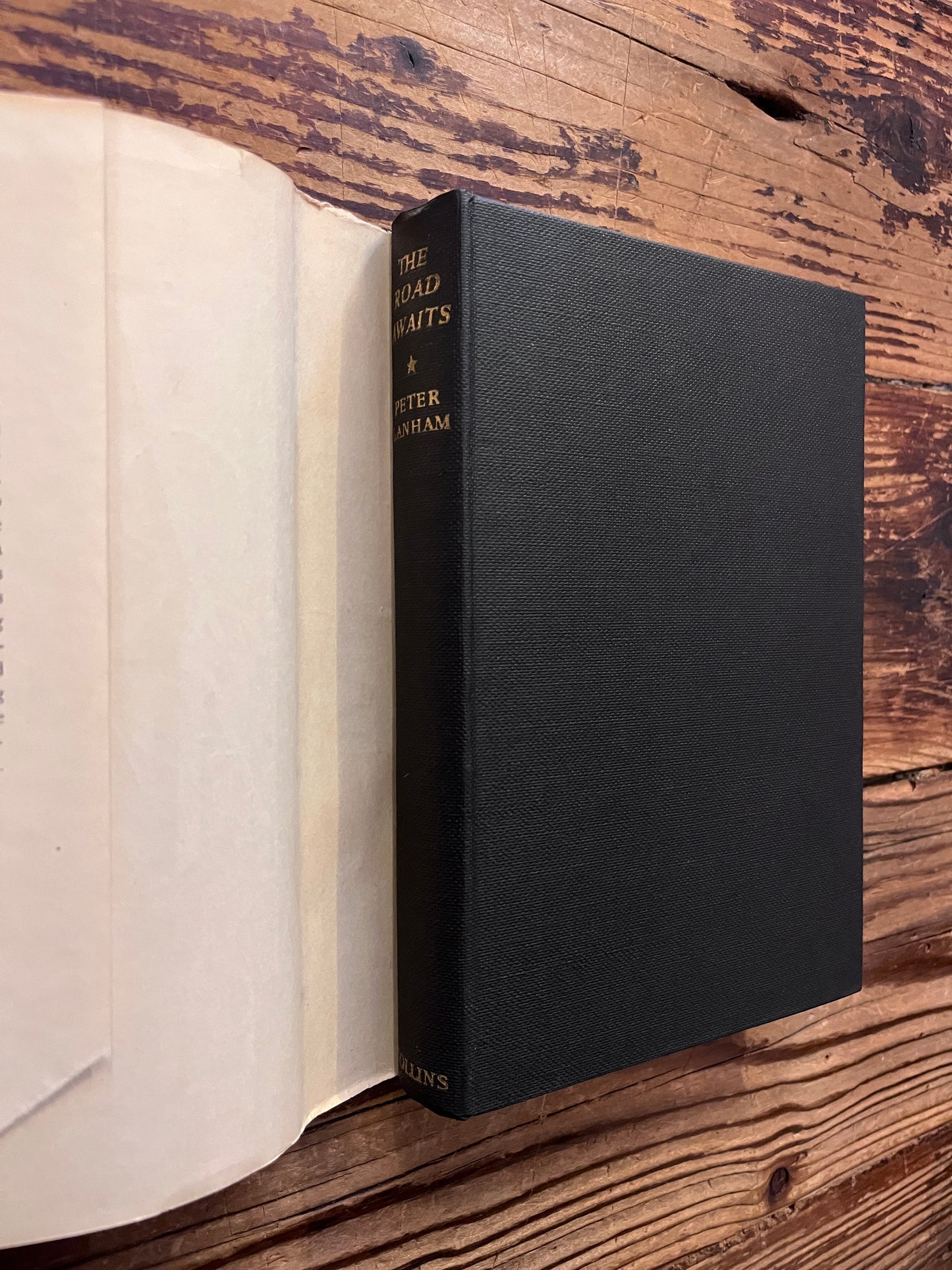 Book titled 'The Road Waits' by Peter Lanham on a wooden surface