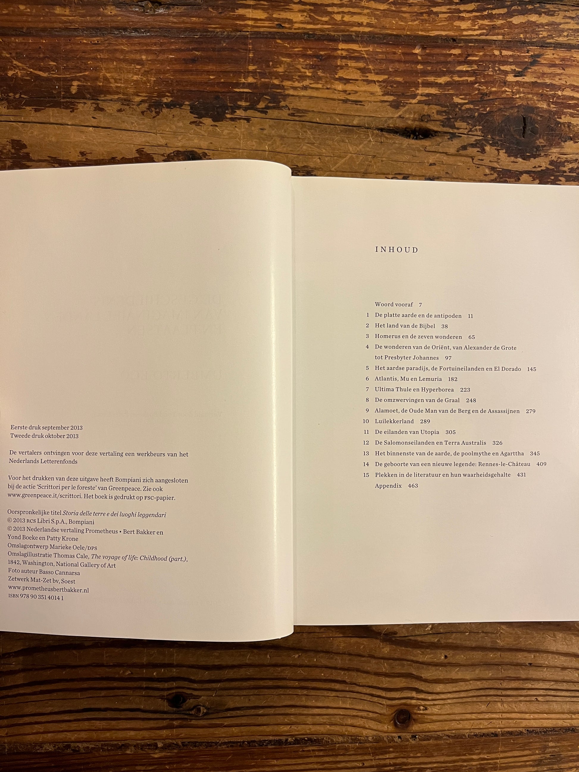 Open boek met de titel 'De Geschiedenis Van Imaginaire Landen En Plaatsen' door Umberto Eco op een houten achtergrond 