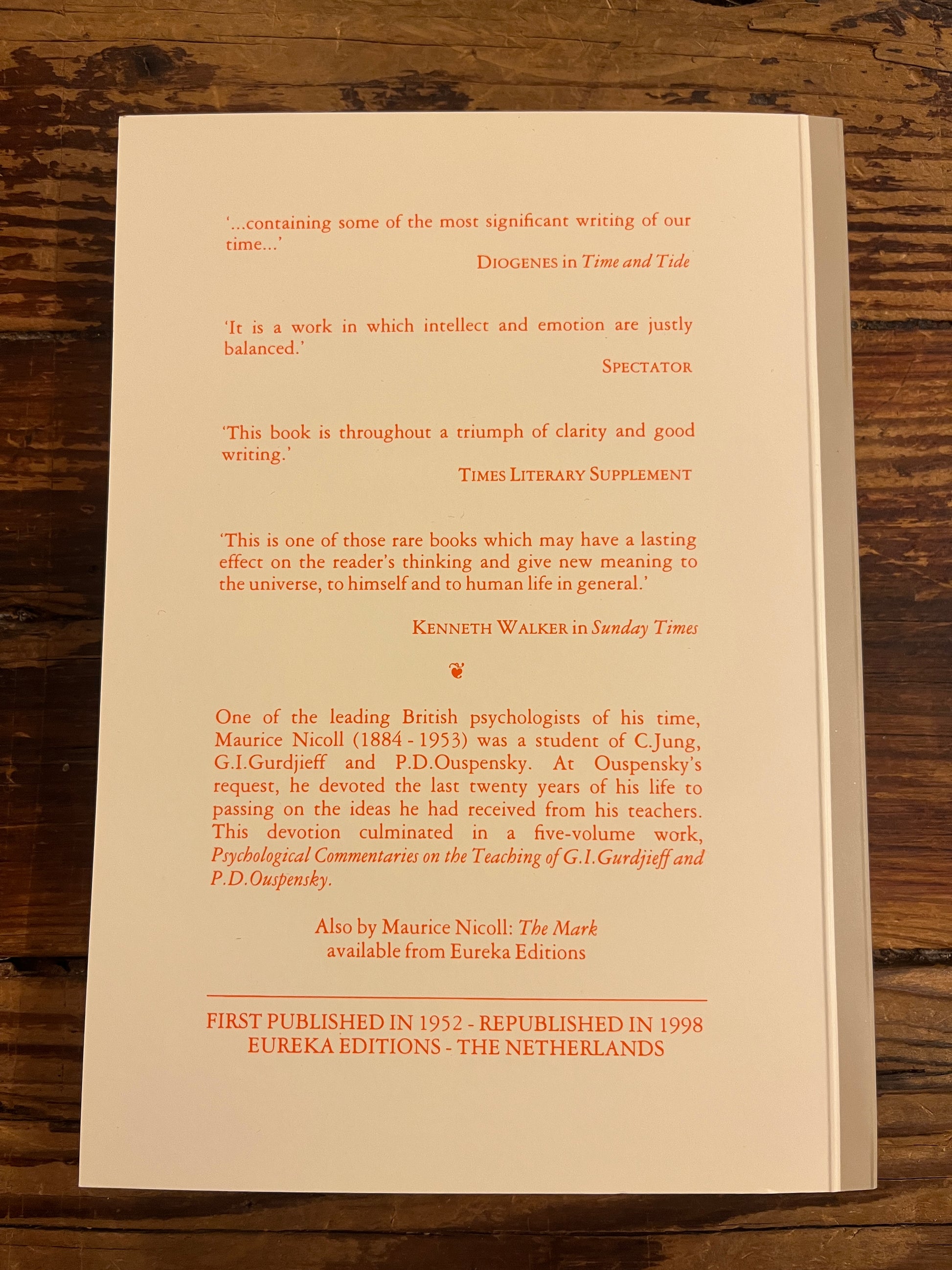 Back cover of book titled 'living time' by Maurice Nicoll on wooden surface