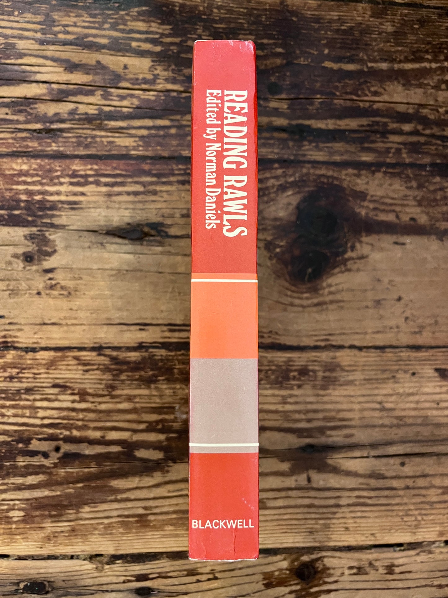 photo of the spine of the book "Critical studies of a theory of justice"on a wooden background