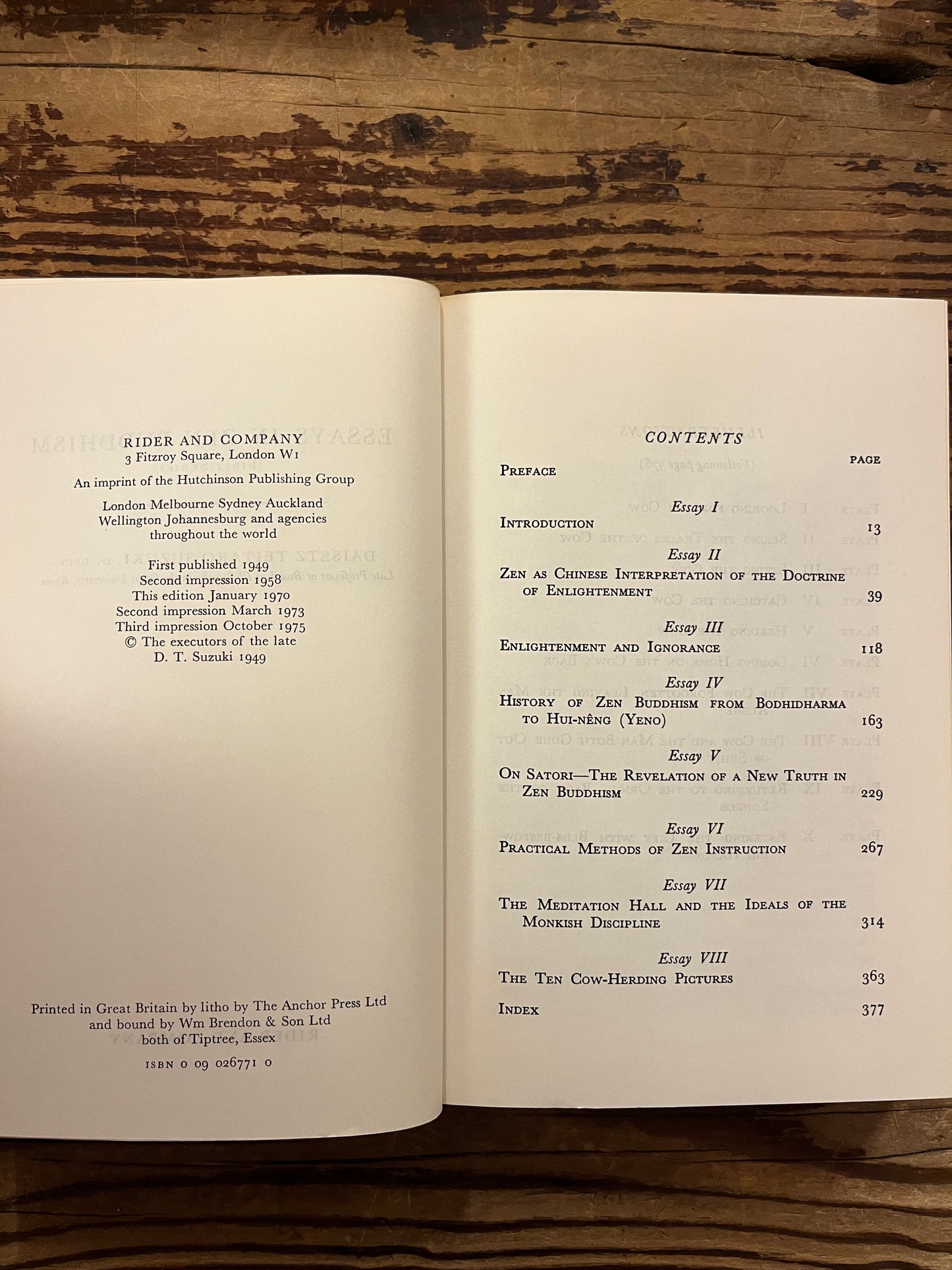 Open book titled 'Essays in Zen Buddhism' by D.T. Suzuki on a wooden surface