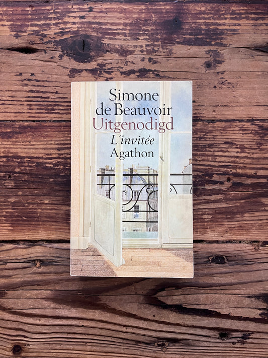 Voorkant van boek met de titel 'L'invitée / Uitgenodigd' door Simone de Beauvoir op een houten achtergrond
