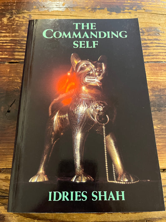 Book titled 'The Commanding Self' by Idries Shah on a wooden surface