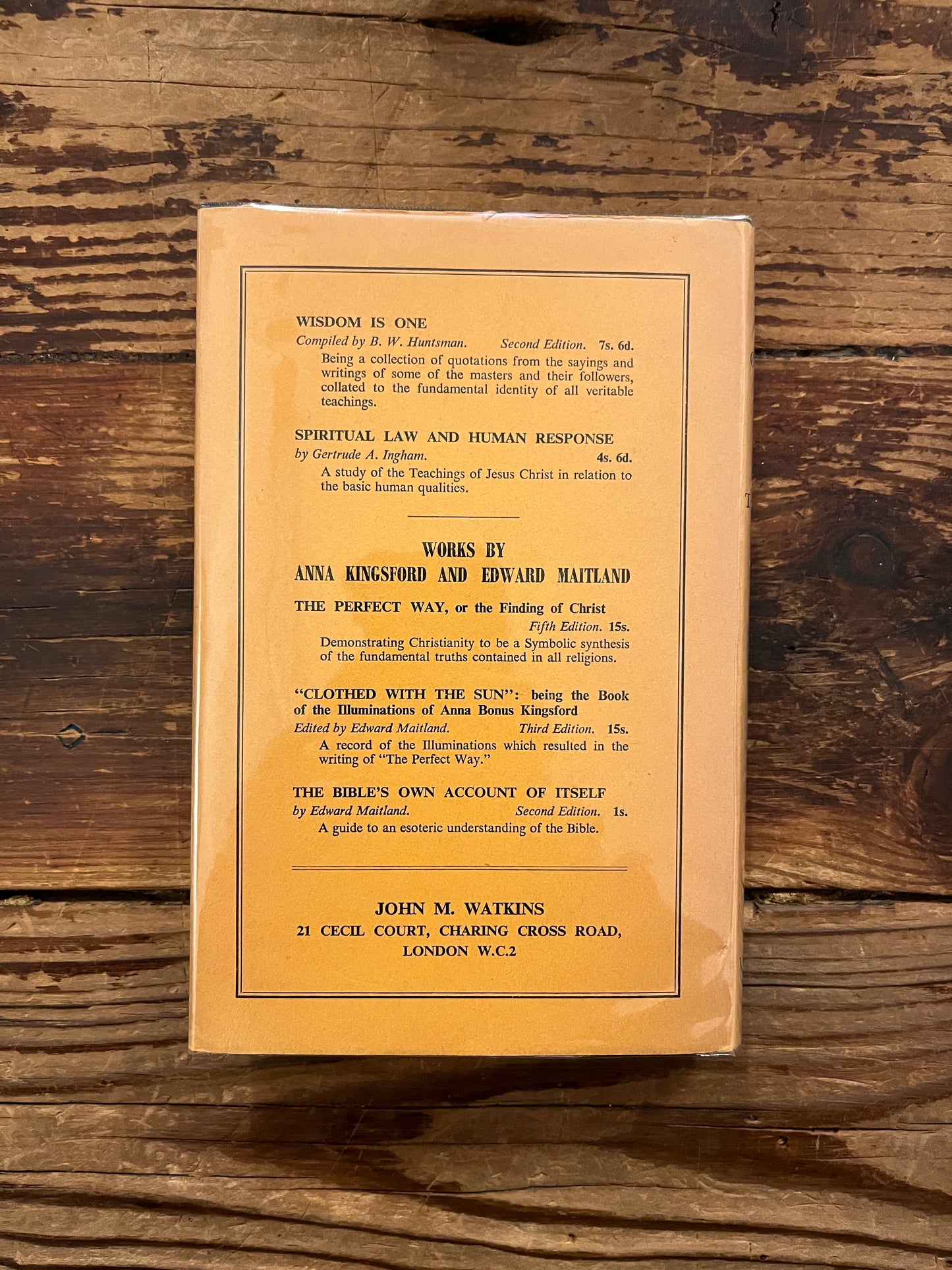 Back cover of Book titled 'The Gospel of the Holy Twelve' by J.R. Ouseley on a wooden surface