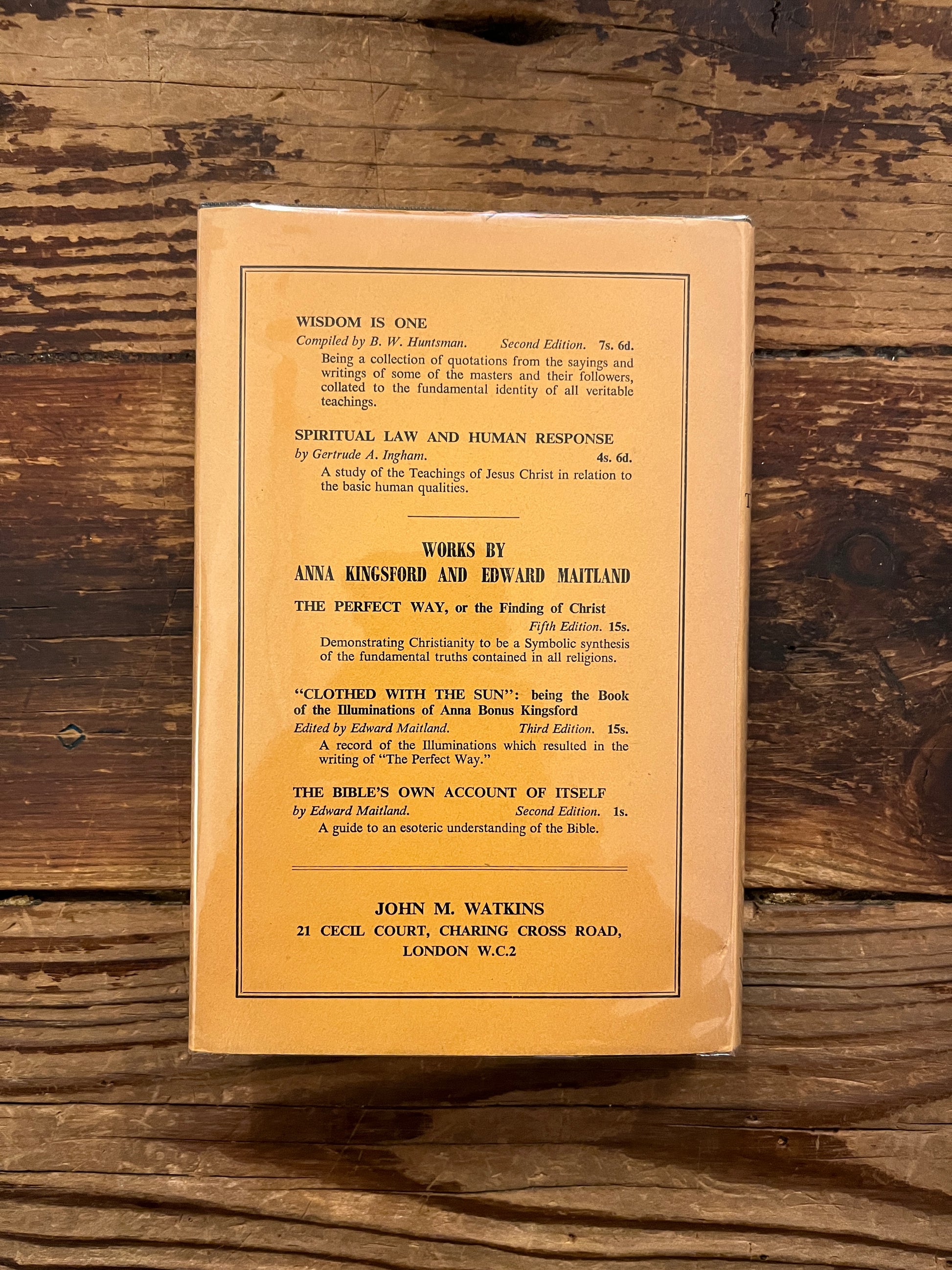 Back cover of Book titled 'The Gospel of the Holy Twelve' by J.R. Ouseley on a wooden surface