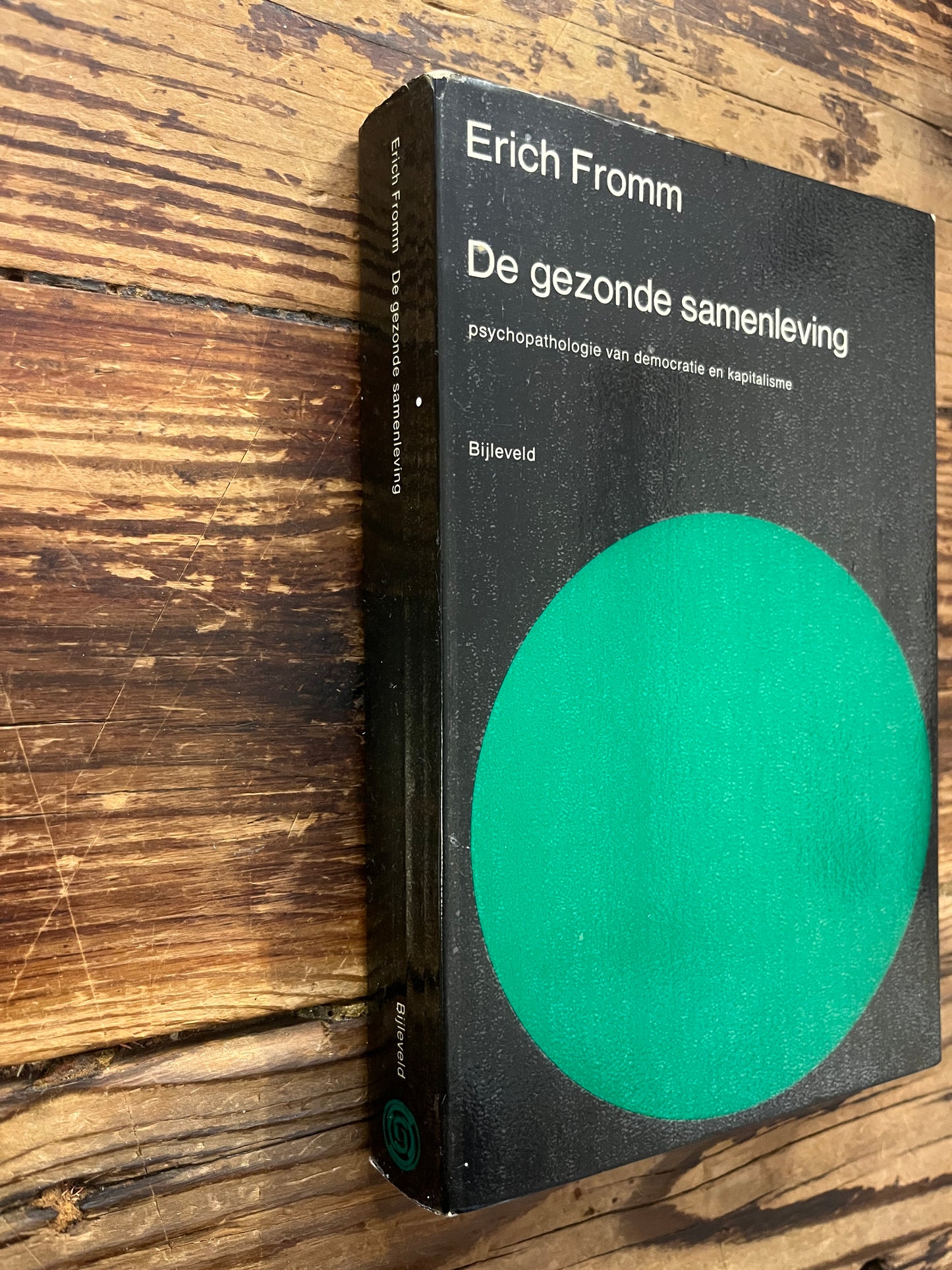 Boek met de titel 'De gezonde samenleving' door Erich Fromm op een houten achtergrond 