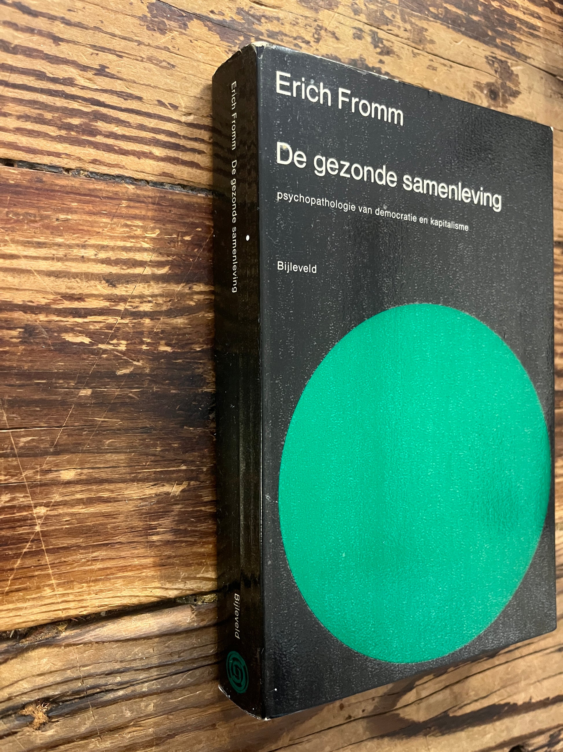 Boek met de titel 'De gezonde samenleving' door Erich Fromm op een houten achtergrond 