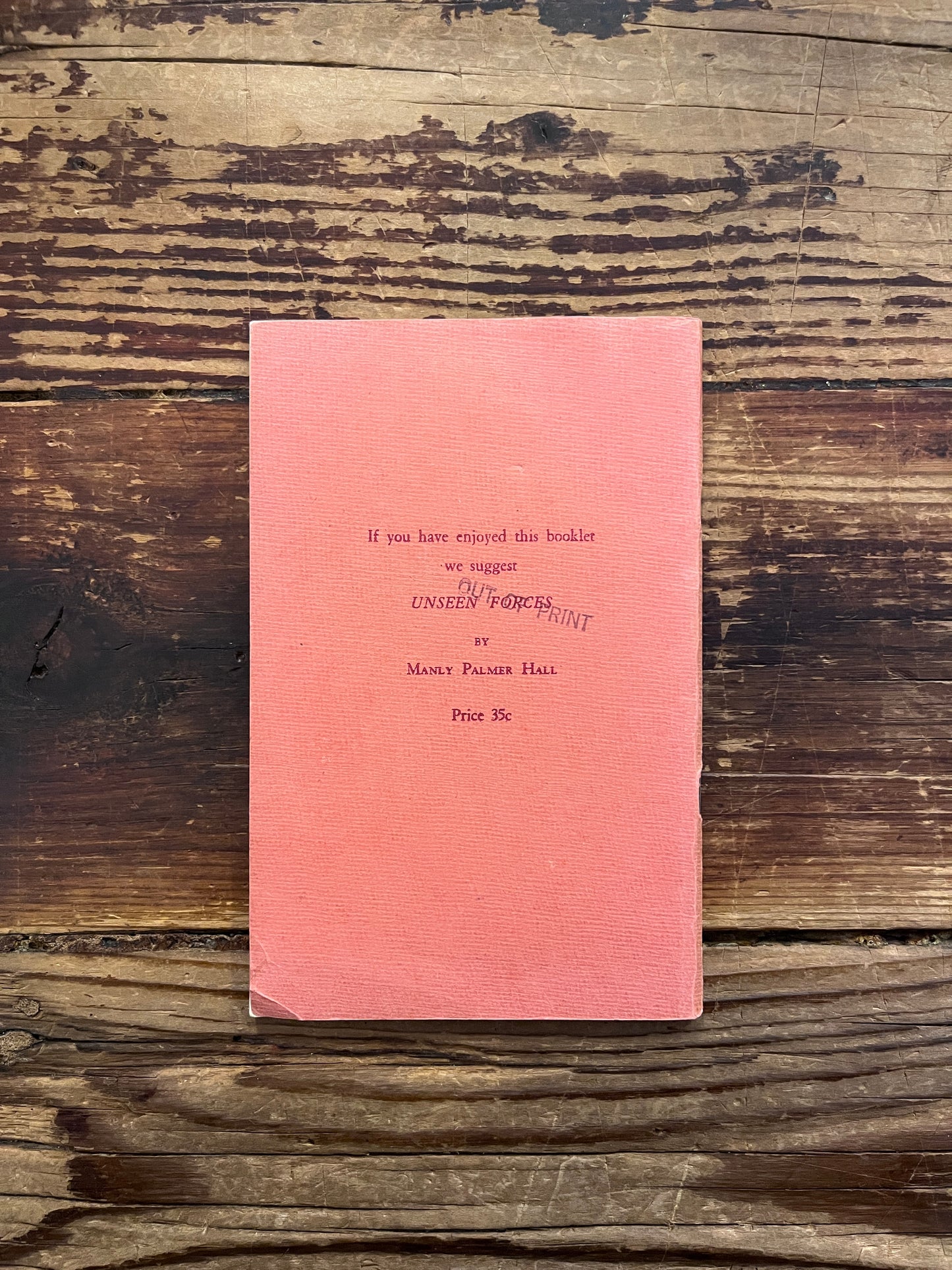 Back cover of book titled 'Super Faculties and Their Culture' by Manly P. Hall on a wooden surface
