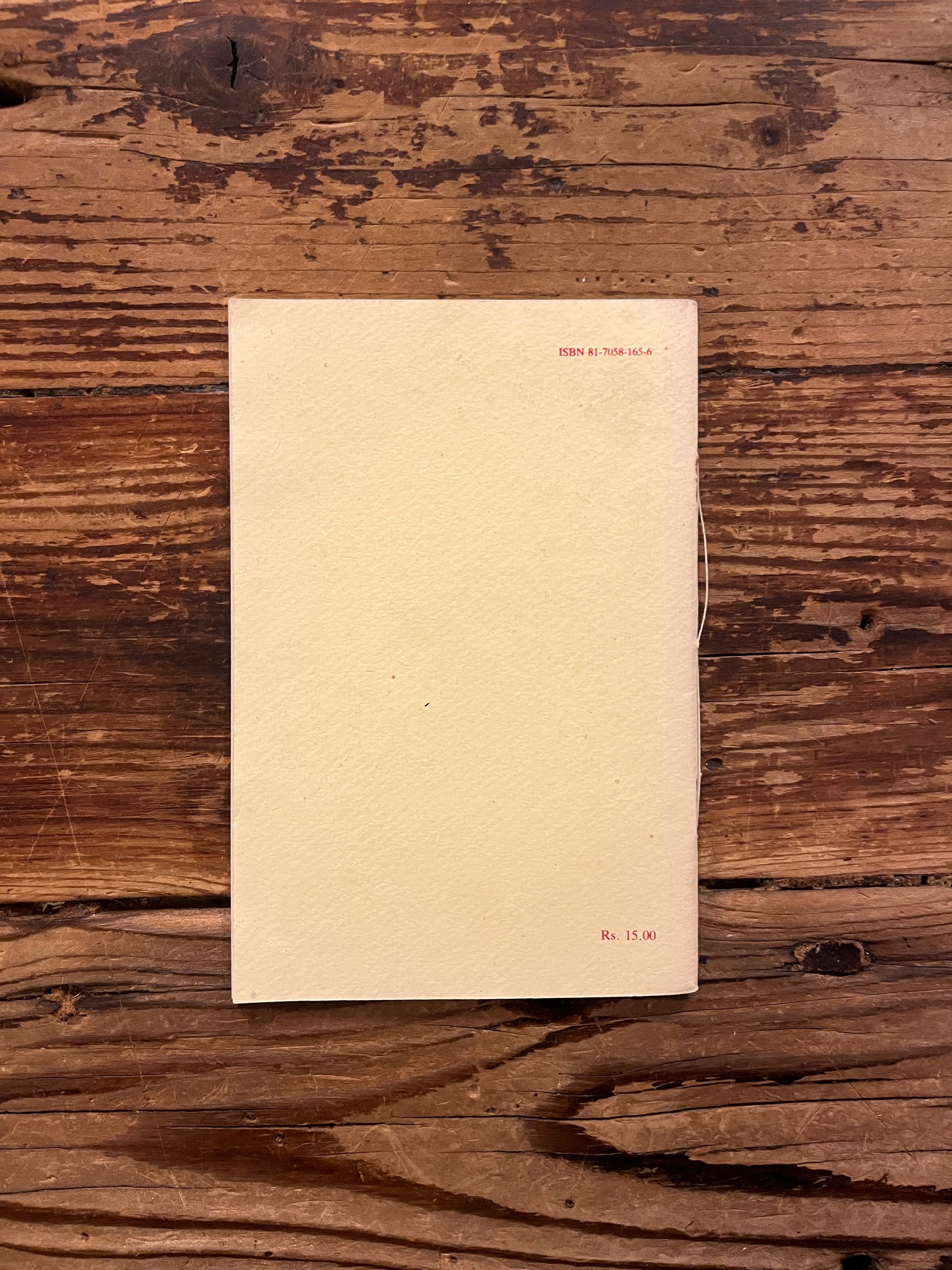 Back cover of book titled 'Ideal and Progress' by Sri Aurobindo on a wooden surface
