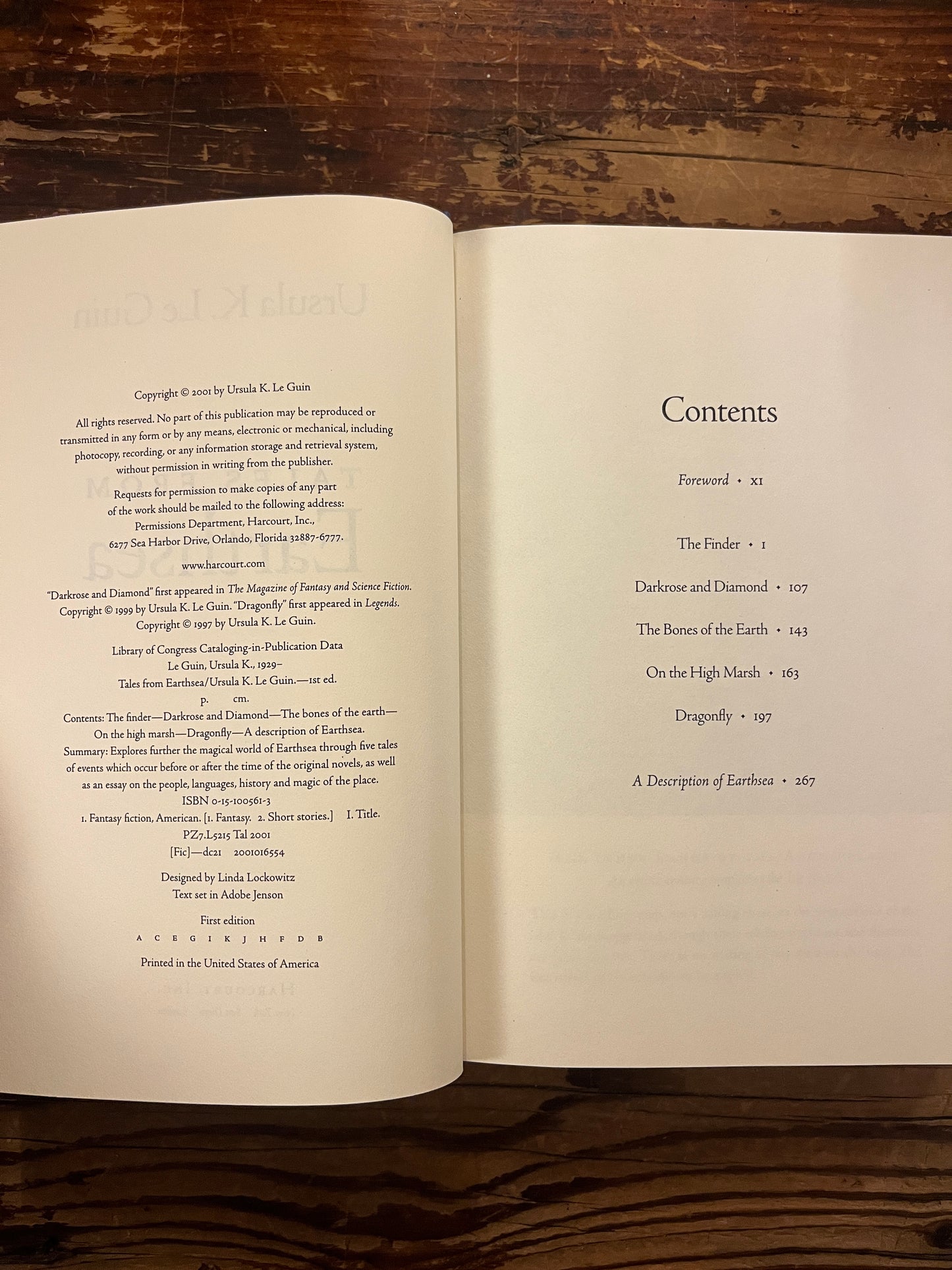 Open book showing the contents of a book titled 'Tales from Earthsea' by Ursula K. Le Guin on a wooden surface